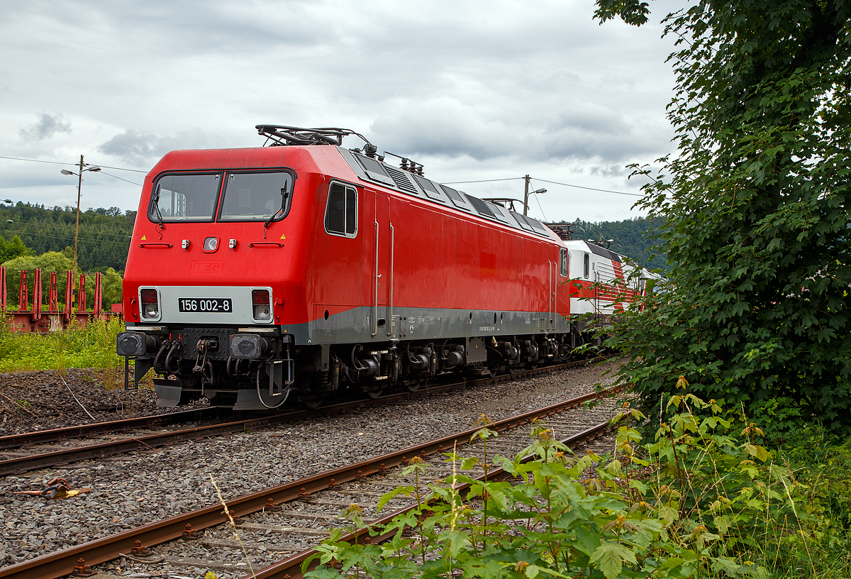 Die 156 002-8 (91 80 6156 002-8 D-FWK) der FWK - Fahrzeugwerk Karsdorf GmbH & Co. KG, ex MEG 802, ex DB 156 002-8, ex DR 252 002-1, ist am 05.07.2021 in Scheuerfeld (Sieg) beim Kleinbahnhof der WEBA (Westerwaldbahn) abgestellt. Dahinter stehen noch die “Weiße Lady” 143 822-5, alias 243 822-4 und die 187 420-5, beide von der EBS - Erfurter Bahnservice GmbH.

Die 156 002-8 wurde 1991 von LEW (VEB Lokomotivbau Elektrotechnische Werke „Hans Beimler“ Hennigsdorf, ab 1992 wieder AEG) unter der Fabriknummer 20005 gebaut und im Mai 1991 als 252 002-1 an die DR - Deutsche Reichsbahn ausgeliefert. Zum 01.01.92 erfolgte die Umzeichnung in DR 156 002-8 und mit dem Zusammenschluss beider Deutscher Bahnen zum 01.01.94 wurde sie zur DB 156 002-8. Bei der DB AG wurde sie 2003 ausgemustert und ging an die MEG - Mitteldeutsche Eisenbahn GmbH in Schkopau, wo sie als MEG 802 geführt wurde. Im Mai 2020 ging sie dann an die FWK - Fahrzeugwerk Karsdorf GmbH & Co. KG in Karsdorf .

Die ehemalige DR Baureihe 252 (ab 1992 BR 156) war die letzte Neuentwicklung einer Elektrolokomotive der Deutschen Reichsbahn. Sie war als Ergänzung zur BR 250 (ab 1992 BR155) vorgesehen.

Da nach der Wiedervereinigung Deutschlands aufgrund des rapide gesunkenen Güterverkehrsaufkommens kein Bedarf mehr für diese Lokomotiven in konventioneller Wechselstromtechnik bestand, wurde die bereits vollzogene Bestellung über die ersten Lieferserie von 70 Lokomotiven storniert. Insgesamt war bis 1995 die Beschaffung von 350 Exemplaren in mehreren Lieferserien geplant.

Grundkonzept:
Während die DR Baureihe 250 konzeptionell weitgehend auf der DR Reihe 242 basierte, wurden bei der Entwicklung der DR Baureihe 252 bewährte Komponenten der DR Baureihe 243 übernommen. Aufgrund der geringen Zeit zwischen dem Abschluss der technischen Bedingungen und der Auslieferung der Musterlokomotiven von weniger als einem Jahr dienten diese vier Vorauslokomotiven vor allem als Erprobungsträger für verschiedene neuentwickelte Baugruppen.

So erhielten die 252 002 bis 004 erstmals für DR-Lokomotiven an Stelle eines rotierenden Umformers für das Drehstrombordnetz einen Hilfsbetriebeumrichter.

Laufwerk
Die Lokomotiven laufen auf zwei dreiachsigen Drehgestellen mit einem Rahmen in geschweißter Stahlbauweise, die weitgehend denen der Baureihe 250/155 entsprechen. Die Querschnitte der Quer- und Längsträger sind kastenförmig ausgeführt. Der Hauptquerträger nimmt den Drehzapfen auf. Als Achslager finden Zylinderrollenlager Verwendung, die mit Lemniskatenlenkern geführt werden. Die Achsen sind auf Wunsch der DR nicht seitenverschiebbar, um einheitliche Lager an allen Radsätzen verwenden zu können. Für die Serienausführung der Baureihe 252 war allerdings geplant, die Seitenverschiebbarkeit der mittleren Achse wieder zu gewährleisten (analog zur Ausführung bei der Baureihe 250/155). 1993/94 erhielten die 252 001 und 003 im AW Dessau seitenverschiebbare Mittelradsätze, die ein Spiel von einem Millimeter zulassen. Vier Schraubenfedern pro Radsatz, die vertikal über zwei hydraulische Dämpfer bedämpft werden, bilden die Primärfederung. Weitere Gummischeiben sind zusätzlich in Reihe geschaltet, um eine bessere Körperschalldämmung zu gewährleisten.
Antrieb

Die Lokomotiven haben einen Kegelringfederantrieb von LEW. Der Motor stützt sich etwa mit der Hälfte seiner Masse über die Kegelringfedern auf dem Radsatz ab, die andere Hälfte lagert mit Gummischubfedern auf den Drehgestellrahmen.

Lokomotivkasten und Bremsausrüstung:
Die vier Lokomotiven verfügen über einen vollständig geschweißten selbsttragenden Lokomotivkasten aus Stahl in Leichtbauweise. Dieser ähnelt dem der Baureihe 120 der DB und ist im oberen Bereich der Front um 19° geneigt, im unteren Bereich um 9°. Somit ergibt sich ein Luftwiderstandsbeiwert von 0,45. Für eine optimale Kopfform führte man Versuche im Windkanal der Technischen Universität Dresden durch. Die Dachhauben über dem Maschinenraum sind in drei Sektionen geteilt und abnehmbar. Die Türen führen in den Maschinenraum, in dem ein Seitengang vorhanden ist. Von dort aus gelangt man über Türen in die Führerstände.

Die Schraubenkupplung und die Hochleistungspuffer sind mit den UIC-Richtlinien 520, 521 und 527-1 konform. Die DR-Einheitszugkästen ermöglichen die Umstellung auf Mittelpufferkupplungen. Des Weiteren befindet sich am Pufferträger ein Schneeräumer.

Die Führerstände entsprechen denen der Baureihe 243 und gewährleisten bei einer Höchstgeschwindigkeit der Lokomotive von 120 km/h einen maximalen Geräuschpegel von 78 dB (A). Die Seitenscheiben sind im Gegensatz zu den Lokomotiven der Baureihen 112 bzw. 243 als Schiebefenster ausgeführt.

Die Lokomotiven verfügt über folgende Bremseinrichtungen:
selbsttätige, mehrlösige Druckluftbremse mit integrierter Ergänzungsbremse;
nicht selbstständige Druckluft-Zusatzbremse:
mechanische Feststellbremse;
fahrleitungsabhängige elektrische Widerstandsbremse (Bremsanschrift KE-GPR-E m.Z).
Ferner verfügen die Lokomotiven über eine Gleitschutzanlage der Firma Knorr (Bauart MGS 1.20)

TECHNISCHE DATEN:
Spurweite: 1.435 mm
Achsanordnung: Co`Co`
Länge über Puffer:  19.500 mm
Drehzapfenabstand: 11.290 mm
Gesamtradstand:  14.660 mm
Treibraddurchmesser:  1.250 mm (neu) /1.160 mm (abgenutzt)
Höhe: 4.650 mm (bei gesenkter Stromabnehmer)
Breite: 3.100 mm
Dienstgewicht:  120,0 t
Höchstgeschwindigkeit: 120 km/h
Stundenleistung: 5.880 kW
Dauerleistung: 5.580 kW
Anfahrzugkraft:  361 kN
Stromsystem: 15 kV, 16,7 Hz ~
Anzahl der Fahrmotoren: 6
Antrieb: LEW-Kegelringfeder
Bremse: Druckluftbremse und el. Widerstandsbremse
Kleinster bef. Halbmesser:  R 140 m
Zugbeeinflussung: PZ80, PZB 90

Gründe für die Nichtbeschaffung einer Serie:
Bei der Deutschen Bundesbahn hatte man zu dieser Zeit mit der Baureihe 120 bereits Erfahrungen mit in Serie gebauten Drehstromlokomotiven, die als deutlich wirtschaftlicher gelten und deren bürstenlose Fahrmotoren deutliche Unterhaltungsvorteile bieten, gewinnen können. Demgegenüber waren die Maschinen der Baureihe 156 noch konventionelle Einphasenlokomotiven mit Reihenschlussmotoren. Insofern bestand nach der deutschen Wiedervereinigung wenig Interesse an einer komplett neu entwickelten Wechselstromlokomotive.

Die neu gegründete Deutsche Bahn AG musste nun die Vor- und Nachteile der zur Serienfertigung anstehenden Baureihen 112 und 156 abwägen. Die DB wollte keine sechsachsigen Lokomotiven mehr beschaffen, da diese einen deutlichen Mehraufwand in Herstellung und Wartung gegenüber den mittlerweile favorisierten vierachsigen Maschinen nach sich ziehen. Des Weiteren war durch den nach der Wende stark rückläufigen Güterverkehr kein Bedarf für reine schwere Güterzugloks mehr vorhanden. Für die Bestellung der Baureihe 112 sprach dagegen, dass es sich um eine bereits von der DR fertig entwickelte, nur noch nicht in Serie bestellte Reisezuglokomotive handelte. Da ein erhöhter Bedarf für Reisezuglokomotiven mit 160 km/h Höchstgeschwindigkeit bestand, fiel die Entscheidung zum Serienbau zugunsten der Baureihe 112. Die vier bereits gefertigten Maschinen der Baureihe 156 blieben somit Einzelstücke.