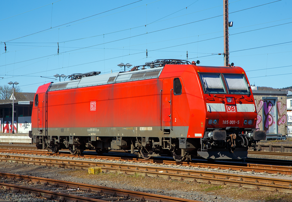 Die allererste der Baureihe 185....
Die 185 001-5 (91 80 6185 001-5 D-DB) der DB Cargo AG ist am 04.04.2020 in Kreuztal abgestellt.
Die TRAXX F140 AC wurde 2000 von DaimlerChrysler Rail Systems (Adtranz) in Kassel unter der Fabriknummer 33398 gebaut. Die Abnahme durch die DB Cargo erfolgte erst Anfang Dezember 2002.

Auf Grund der wachsenden internationalen Aktivitäten von DB Cargo wurde für neue elektrische Güterzuglokomotiven Zweisystemfähigkeit für den Einsatz mit 25 Kilovolt bei 50 Hertz gefordert, um mit den Lokomotiven auch Frankreich, Luxemburg und Dänemark anfahren zu können. Die bestehende Option auf weitere Lokomotiven der Baureihe 145 wurde daher entsprechend abgewandelt wahrgenommen.

Im Januar 2000 konnte der Hersteller Adtranz (ab 2001 Bombardier) mit der 185 001 das erste Exemplar einer Mehrsystemvariante der Baureihe 145 präsentieren. Technisch sind die 185er eine Weiterentwicklung der 145, auch flossen Erkenntnisse aus der Entwicklung der Baureihe 146 in die Lokomotiven mit ein. Insgesamt wurden 405 Lokomotiven der Baureihe 185 (200 F140 AC1 sowie 205 F140 AC2) beschafft, wodurch diese die derzeit am häufigsten im deutschen Eisenbahnnetz anzutreffende Elektrolokomotive ist. Mit ihr wurden vor allem die alten Lokomotiven der Baureihe 140 ersetzt. Der Stückpreis einer Lokomotive der Baureihe 185 betrug im Jahr 2000 circa 4,85 Millionen DM (rund 2,5 Millionen Euro).
