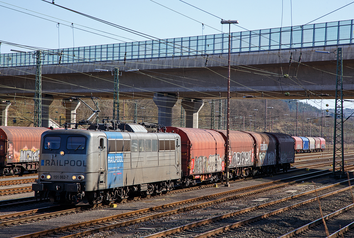 Die an die DB Cargo AG vermietete Railpool 151 062-7 (91 80 6151 062-7 D-Rpool) steht am 31.03.2021, mit einem kurzen Coilzug, im Rbf Kreuztal zur Abfahrt bereit.

Die Lok wurde 1974 von Henschel & Sohn in Kassel unter der Fabriknummer 31805 gebaut und an die Deutsche Bundesbahn geliefert. Bis 31.12.2016 geh�rte sie zur DB Cargo AG. Zum 01.01.2017 wurden je 100 sechsachsige elektrische Altbau-Lokomotiven der Baureihen 151 und 155 an ein Konsortium aus dem Lokvermieter Railpool verkauft. Die DB Cargo mietet daraufhin 100 Loks von Railpool wieder an. Die anderen Maschinen werden dem freien Markt angeboten.

Wie auch die Werbung auf  ihr zeigt: Die Lok gibt es im Ma�stab 1:1 bei RAILPOOL und im Ma�stab 1:87 bei Roco und im Ma�stab 1:160 bei Fleischmann. Wobei mir pers�nlich gef�llt sie in der Farbgebung nicht gerade. 
