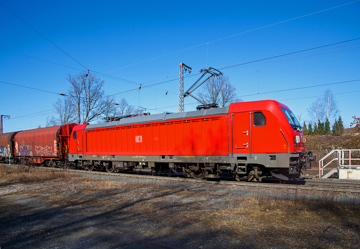 Die DB Cargo 187 197 (91 80 6187 197-9 D-DB) fährt am 10.03.2022 mit einem gemischten Güterzug durch Wilnsdorf-Rudersdorf (Kr. Siegen) in Richtung Dillenburg. 

Die Bombardier TRAXX F140 AC3 wurde 2021 von der Bombardier Transportation GmbH in Kassel unter der Fabriknummer  KAS 35744 gebaut.  Die TRAXX F140 AC3 Varianten der DB Cargo (BR 187.1) haben keine Last-Mile-Einrichtung. Die Lok hat nur die Zulassung für Deutschland, die Höchstgeschwindigkeit beträgt 140km/h. Die Lokomotiven können in gemischter Mehrfachtraktion mit BR185 und BR186 eingesetzt werden.