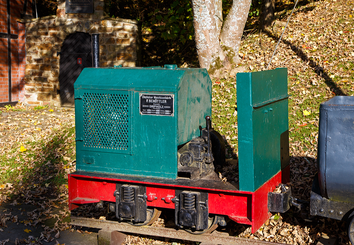 Die DIEMA Feldbahnlok vom Typ DL 6, Fabriknummer 1983, Baujahr 1956, Leistung 18 KW, Gewicht 1.115 kg, von 700 auf 600 mm um gespurt, als Denkmallok am 28.10.2021 mit zwei Grubenwagen beim Wodanstolln in Neunkirchen-Salchendorf. Wobei eigentlich ganz stilecht bzw. geschichtlich richtig ist dieses Denkmal nicht, denn die Lok ist eine Feldbahnlok. Bei den Siegerländer Erzgruben kamen aber Gubenloks zum Einsatz. 

Die DL 6 der Diepholzer Maschinenfabrik Fritz Schöttler (Diema) ist eine Diesellokomotive für Feldbahnen. Mit einem Gewicht von etwa 1 t, einer Länge von ca. 1,7 m und einem Achsstand von 0,5 m gehört sie zu den kleinsten Lokomotiven überhaupt. Die DL 6 entstand 1955 als kleinere und leistungsschwächere Version der DL 8. Insgesamt wurden 220 Exemplare gebaut, womit die DL 6 zu den erfolgreichsten Diema-Konstruktionen gehört. Eingesetzt wurden die Lokomotiven vor allem von kleinen Torfabbaubetrieben. Die letzte Lokomotive wurde im September 1970 ausgeliefert.

Die Lokomotiven sind auf einem geschweißten Außenrahmen aufgebaut. Die Breite des Rahmens hing von der Spurweite ab, insbesondere gab es eine Version für die in den Niederlanden verbreitete 700-mm-Spur, zu diese die Lok hier gehört. In der DL 6 kommen luftgekühlte Einzylinder-Dieselmotoren zum Einsatz. Die Leistungsübertragung erfolgt über einen Keilriemen vom Motor auf ein mechanisches Zweiganggetriebe und von dort aus über Rollenketten auf die beiden Achsen. Diese waren zunächst über Evolutfedern abgestützt, später wurden Schraubenfedern eingebaut.

Der Fahrersitz ist, wie bei Lokomotiven dieser Kategorie üblich, quer zur Fahrtrichtung eingebaut, so dass der Fahrer seine Position bei Fahrtrichtungswechseln nicht ändern muss. Motor und Getriebe nebst Schalthebeln befinden sich dabei rechts vom Fahrer, der Bremshebel links. Wobei bei dieser Lok der Fahrersitz fehlt.
