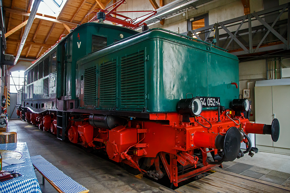 Die Güterzug-Elektrolokomotive 254 052-4 (97 80 9194 052-7 D -   ) des Vereins  Freunde des historischen Lokschuppens 1905 Freilassing e.V. , ex DR 254 052-4, ex DR E 94 052, ex SZD TEL 94-052, am 11.09.2022 in der Lokwelt Freilassing. 

Das Deutsche Krokodil wurde 1941 von der AEG (Allgemeine Elektrizitäts-Gesellschaft) in Hennigsdorf bei Berlin unter der Fabriknummer 5331 gebaut und im Januar 1943 an die Deutsche Reichsbahn geliefert.

Der Lebenslauf der Freilassinger Vereinslok 254 052-4:
• 11.12.1941  Endabnahme, Probefahrt von München Hbf zum Brenner und zurück.
• 12.12.1941  Auslieferung als DRB E 94 052 und bis April 1945 in Bayern
• April 1945 bis Mai 1946 beim Bw Probstzella in Thüringen
• Von Mai 1946 bis August 1952 als Reparationsleistung in die UdSSR (Sowjetunion) nach Workuta nördlich des Polarkreises als SZD TEL 94-052 (umgespurt auf Russische Breitspur)
• August 1952 bis Juli 1957 Wiederaufbau im  RAW Dessau, nach Rückgabe an die DR (DDR) in einem  grauenhaften Zustand, eingereiht als DR E 94 052. 
• Zum 01.07.1970 Umzeichnung in DR 254 052-4 
• Nach Führerhausbrand im August 1990, z-Stellung und zum 30.01.1992  Ausmusterung.
• Von 1994 - 1998  Standort Staßfurt (privat).
• Von 1998 - 2002 EFO Eisenbahnfreunde Oberberg, Standort EM Dieringhausen.
• Im Juni 2002 erfolgte die Betriebsfähige Aufarbeitung in Dessau, danach Vermietung an die PEG
• 2002 – 2006 als E 94.01der PEG - Prignitzer Eisenbahngesellschaft, Einsatz im Güterzugverkehr
• 2006  als 254 052-4Neulack im DR-Farbschema
• Fristablauf  zum 01.08.2010  
• 2010 – 2013 als E 94 052 bei LEG (Leipziger Eisenbahnverkehrsgesellschaft) und Leihgabe an das SEM (Sächsisches Eisenbahnmuseum) .
• Seit 2013 als Vereinslok 254 052-4 der Freunde des historischen Lokschuppens 1905 Freilassing e.V., Standort Lokwelt Freilassing, leider nur zu bestimmten zu besichtigen. 

Die Baureihe E 94 (ab 1968 DB-Baureihe 194, ab 1970 DR 254, ÖBB Reihe 1020) bezeichnet eine Baureihe sechsachsiger schwerenr Elektrolokomotiven der Deutschen Reichsbahn, die für den Güterzugdienst konzipiert waren und ab 1940 gebaut wurden. Außerdem sollten sie die Durchlassfähigkeit schwieriger Rampenstrecken, wie zum Beispiel der Geislinger Steige, der Frankenwaldbahn, der Arlbergbahn und der Tauernbahn erhöhen. Sie trugen den Spitznamen „Deutsches Krokodil“ manchmal auch „Eisenschwein“.

Die Co’Co’-Loks stellten eine direkte Weiterentwicklung der Baureihe E 93 dar, von der sich die E 94 äußerlich auf Anhieb durch die fischbauchförmigen und gelochten Langträger des Brückenrahmens sowie durch die andere Anordnung der seitlichen Fenster und Lüftungsgitter unterscheiden lässt. Die AEG lieferte bis zum Ende des Zweiten Weltkrieges 146 dieser auch KEL 2 (Kriegsellok) genannten Maschinen mit den Betriebsnummern E 94 001 bis 136, 145 und 151 bis 159. Beim Fahrzeugbau wurden zunehmend sogenannte Heimstoffe verwendet. Als Kriegslok hatte ihr Bau Priorität. Die Loks waren für 90 km/h Höchstgeschwindigkeit zugelassen.

Die Loks der Reihe E 94 waren in der Lage, Güterzüge mit 2.000 Tonnen in der Ebene mit 85 km/h, 1600 Tonnen über 10 Promille Steigung mit 40 km/h, 1000 Tonnen über 16 Promille mit 50 km/h und 600 Tonnen über 25 Promille mit 50 km/h zu ziehen.

Nach dem Zweiten Weltkrieg verblieben die meisten Loks bei der Deutschen Bundesbahn (DB). Aus vorhandenen Teilen wurden auch nach Kriegsende noch Lokomotiven fertiggestellt und bei der DB und den Österreichischen Bundesbahnen (ÖBB) in Betrieb genommen.

Die DB ließ zwischen 1954 und 1956 weitere Lokomotiven mit den Nummern E 94 178 bis 196 und E 94 262 bis 285 nachbauen und erwarb vier weitere von der Deutschen Reichsbahn, so dass sie insgesamt 124 Fahrzeuge im Bestand hatte. 1968 zeichnete die DB die E 94 gemäß ihrem Baureihenschema in die UIC-Baureihenbezeichnung 194 um.

Der Einsatz der Baureihe 194 bei der Bundesbahn beschränkte sich ausschließlich auf den süddeutschen Raum. Neben der Beförderung von Güterzügen waren sie als Schiebelokomotiven auf der Geislinger Steige und der Spessartrampe im Einsatz.

Die E 94 bei der DR nach 1945:
Im Bereich der Deutschen Reichsbahn waren 30 Lokomotiven verblieben, von denen aber zehn schadhaft abgestellt waren. Davon wurden nach dem Ende des elektrischen Betriebs (im März 1946) 25 Stück in die Sowjetunion als Reparationsgut verbracht, wie auch diese Lok hier. Dort wurden sie in der Mehrzahl für einen Versuchsbetrieb bei Perm auf 1.520 mm umgespurt und mit SA3-Mittelpufferkupplung ausgerüstet. Die nicht dafür ausgelegten Drehgestelle büßten dabei an Stabilität ein. Wegen des Platzmangels musste man auch die Radsterne abdrehen.

1952 und 1953 wurden von der UdSSR die 25 Lokomotiven wieder an die DR zurückgegeben. Wegen der geänderten Spurweite erfolgte das in der Regel in drei Teile zerlegt und auf Flach- bzw. Tiefladewagen verladen.

TECHNISCHE DATEN:
Spurweite: 1.435 mm (Normalspur)
Achsformel: Co’Co’
Länge über Puffer: 18.600 mm
Drehzapfenabstand: 10.000 mm
Achsabstand im Drehgestell: 4.600 mm
Treibraddurchmesser: 1.250 mm
Dienstgewicht: 118,7 t
Höchstgeschwindigkeit: 90 km/h
Stundenleistung: 3.300 kW
Dauerleistung: 3.000 kW
Anfahrzugkraft: 363 kN
Stromsystem: 15 kV 16⅔ Hz
Anzahl der Fahrmotoren: 6
Antrieb: Tatzlager
Bauart Fahrstufenschalter:  Handbetätigtes Nockenschaltwerk mit Zusatztrafo und Feinregler, eine halbe Umdrehung am Fahrstufenschalter bedeutete eine Fahrstufe
Bremse:  einlösige Druckluftbremse mit Zusatzbremse und elektrische Widerstandsbremse Kbr/K-GP m.Z. (Widerstandsbremse bei der DR ab 1981 ausgebaut)
