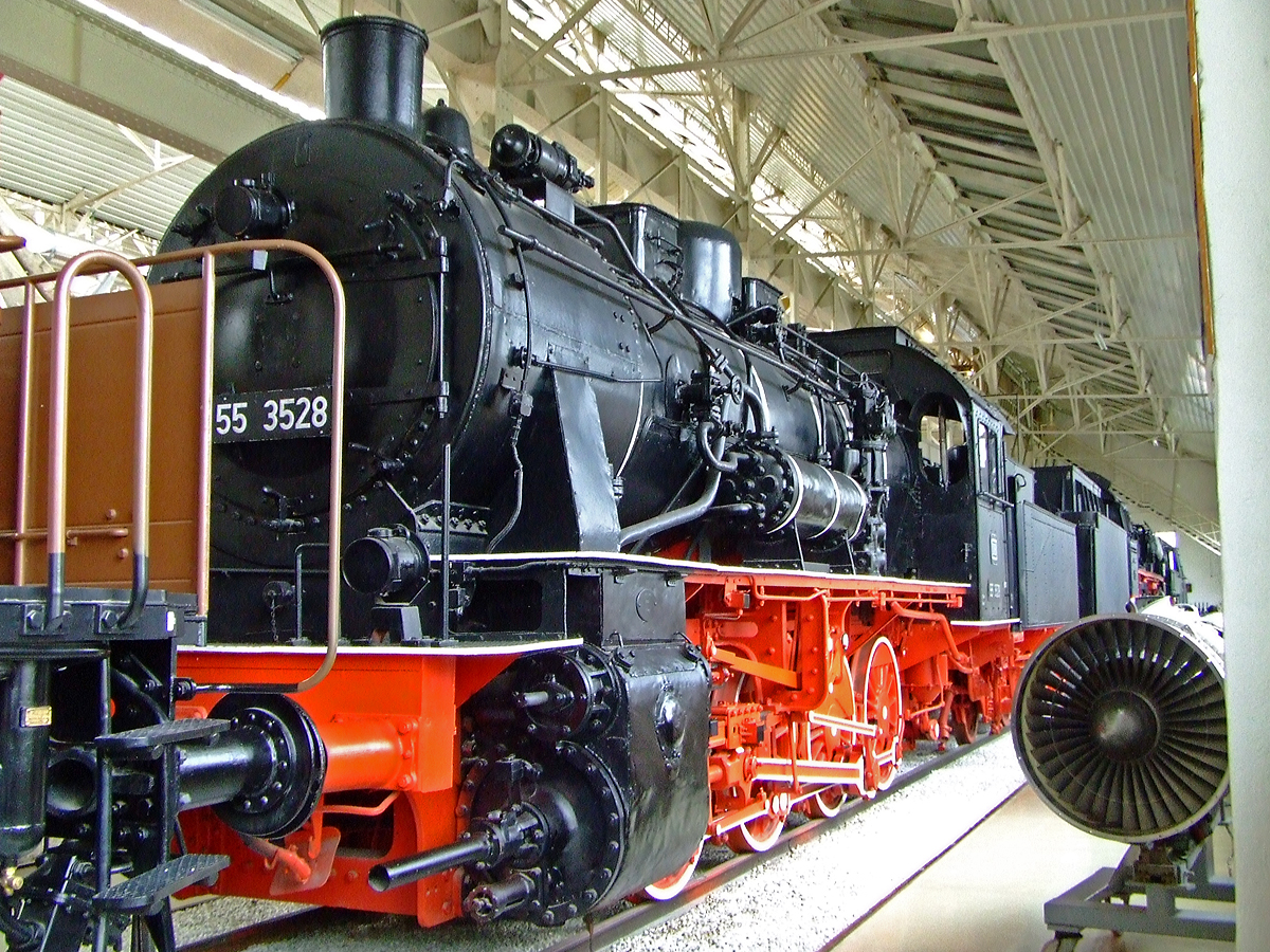 
Die G�terzuglokomotiven 55 3528, ex DB 055 528-4, ex NS 4114, ex KPEV 5256 M�nster, am 02.10.2010 im Technik Museum Speyer. 

Die ehemalige Preu�ische G 8.1 M�nster 5256 wurde 1915 von HANOMAG (Hannoversche Maschinenbau-Actiengesellschaft, vorm. Georg Egestorff) unter der Fabriknummer 7587 gebaut. Nach dem Zweiten Weltkrieg blieb sie erst bei der NS in den Niederlanden bis sie 1947 wieder nach Westdeutschland zur HVE - Hauptverwaltung der Eisenbahnen des amerikanischen und britischen Besatzungsgebiets als 55 3528 kam. So wurde sie wieder zum 07.09.1949 in die neu entstandene Deutsche Bundesbahn als 55 3528 eingereiht. Lange war die Lok beim BW in Dillenburg beheimatet, wo zum 01.01.1968 die Umzeichnung in DB 055 528-4 erfolgte. So fuhr sie dann bis zur Ausmusterung am 19.09.1969. Von 1971 bis 1983 war sie dann als Denkmal (durch die Fa. Walzen Irle GmbH) in Netphen-Deuz (Siegerland) aufgestellt. Im Jahr 1983 ging sie ans Auto- und Technikmuseum Sinsheim und 1991 letztendlich ins Technik Museum Speyer.

Am 27. Juni 1969 wurde die letzte Lok der Baureihe 55 des Bw Dillenburg und auch der Bundesbahndirektion Frankfurt/M, die hiergezeigte 55 3528, mit einer Sonderfahrt verabschiedet. Die Rangieraufgaben im Bahnhof, die immer zu den Hauptaufgaben der Baureihe 55 in Dillenburg gez�hlt hatten, wurden von den Dieselloks der Baureihe V 60 des Bw Gie�en �bernommen, die ab diesem Zeitpunkt ihre Arbeit aufnahmen. 

Obwohl die G 8.1, nach der BR 52, zweith�ufigste gebaute Lokomotivtype in Deutschland war, sind in Deutschland nur zwei Loks erhalten geblieben. Neben dieser 55 3528 ist es die 55 3345 (ex DB 055 345-3, ex Cassel 5159, Henschel 1915) heute im Eisenbahnmuseum Bochum.

Die Dampflokomotivbaureihe Preu�ische G 8.1 war eine von Robert Garbe durchgef�hrte Weiterentwicklung der G 8 und wurde zun�chst als „Verst�rkte Normalbauart“ bezeichnet. Sie hatte einen gr��eren Kessel und ein daraus folgendes h�heres Gewicht war auch beabsichtigt, um durch das h�here Reibungsgewicht die Zugkraft ebenso zu erh�hen. Durch den hohen Achsdruck konnte die G 8.1 allerdings nur auf Hauptbahnstrecken eingesetzt werden. Als Einsatzgebiet kam zum schweren G�terverkehr sp�ter auch der schwere Rangierdienst hinzu.

Die G 8.1 war die am h�ufigsten gebaute L�nderbahnlokomotive und nach der 20 Jahre sp�ter gebauten DR-Baureihe 52 die zweith�ufigst gebaute Lokomotivtype in Deutschland. F�r die Preu�ischen Staatseisenbahnen und zuletzt f�r die Deutsche Reichsbahn wurden allein 4.958 Exemplare hergestellt. Es wurden aber auch einige ins Ausland verkauft.

Infolge des Waffenstillstands am Ende des Ersten Weltkriegs gelangten 459 Maschinen zur PKP, sowie weitere drei an die Freie Stadt Danzig und wurden dort als Reihe Tp4 gef�hrt.

Die Reichsbahn �bernahm 1925 insgesamt 3.133 preu�ische Loks als Baureihe 55.25–56 und 55.58. Im Jahr 1935 kamen weitere 43 Lokomotiven aus dem Saarland als 55 5623–5665 in den Bestand der Reichsbahn, die letzte davon stammte urspr�nglich von den Reichseisenbahnen in Elsa�-Lothringen. Im Zweiten Weltkrieg wurden zahlreiche Lokomotiven aus Polen und Litauen als Zweitbesetzungen in die Baureihe 55 eingereiht. 

Mehr als 1.000 Fahrzeuge gab es noch nach Ende des Zweiten Weltkrieges. 1968 hatte die Deutsche Reichsbahn noch 150 Fahrzeuge und die Deutsche Bundesbahn 50, die sie ab 1968 als Baureihe 055 bezeichnete. Die letzte G 8.1 der Deutschen Bundesbahn, die 055 538-3, wurde am 21. Dezember 1972 aus dem Dienst genommen. Auch in Polen wurden noch 302 Exemplare der Tp4 eingesetzt, die bei der PKP ebenfalls erst 1972 komplett au�er Dienst gestellt wurden.

TECHNISCHE DATEN:
Gebaute Anzahl: 5.155
Baujahre: 	1913 bis1921
Spurweite: 	1.435 mm (Normalspur)
Bauart: D h2
Gattung: G 44.18
L�nge �ber Puffer: 18.290 mm mit Tender 
Leergewicht (ohne Tender) 62,2 t
Dienstgewicht (ohne Tender): 69,9 t
Radsatzfahrmasse:  17,6 t
H�chstgeschwindigkeit: 55 km/h
Indizierte Leistung:  1.260 PS  (927 kW ) 
Treibraddurchmesser: 	1.350 mm
Zylinderdurchmesser: 	600 mm
Kolbenhub: 660 mm
Kessel�berdruck: 14 bar
Tenderbauart: pr 3 T16.5 
Wasservorrat: 16,5 m�
Kohlevorrat: 7 t
