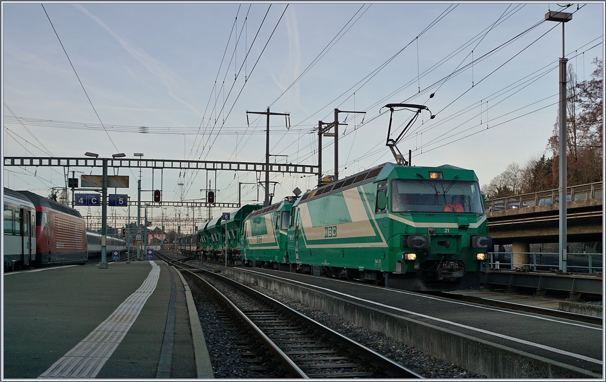 Die Kreuzung zweier Züge geschieht in der Regel, dass die beiden aus unterschiedlichen Richtung kommenden Züge sich kreuzen und dann weiter fahren. Seit kurzem kreuzen sich in Morges leere und volle Schüttgutgüterzüge der BAM MBC, die dabei auch die Traktion, Spurweite und Fahrrichtung wechseln. 
Ein Kaisermanöver vom Feinsten, welches hier Schritt für Schritt gezeigt werden soll: 
Während die Re 4/4 II (UIC 91 85 4420 506 8 CH MBC) mit ihrem leeren Zug von Gland schon vor meiner Ankunft ankam und nun im östlichen Bahnhofskopf auf einem Ausziehgleis wartet, erreicht der volle Schüttgutzug mit den beiden Ge 4/4 21 und 22 Morges.
22. Feb. 2017