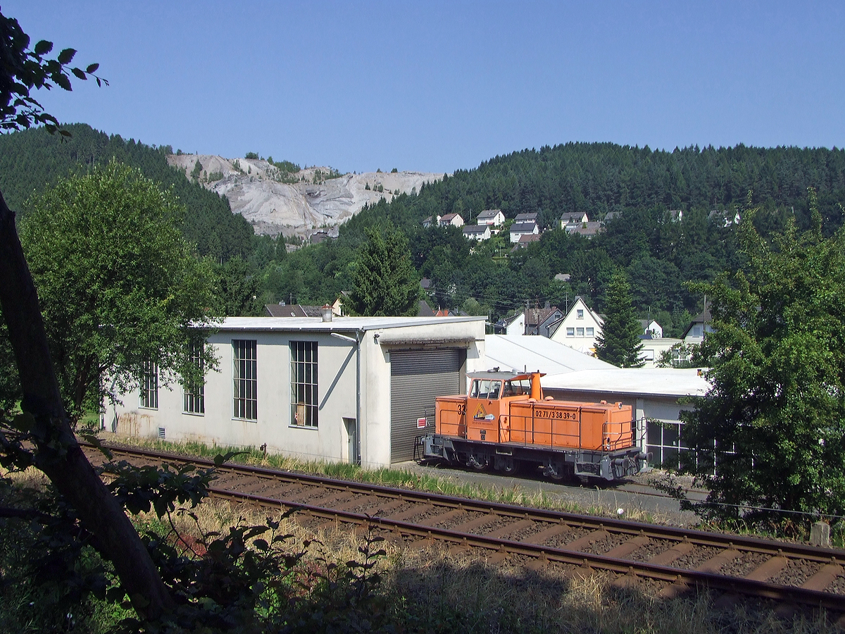 Die Lok 33 der Kreisbahn Siegen-Wittgenstein steht am 02.07.2008 vorm Lokschuppen in Herdorf am 02.07.2008.

Die Lok ist eine MaK G 763 C, sie wurde 1993 von der Maschinenbau Kiel GmbH (MaK) unter der Fabriknummer 700110 gebaut und an die damalige Siegener Kreisbahn GmbH geliefert. Kurz nach der Aufnahme, wurde sie 2008 an die K+S Kali GmbH verkauft, dort wird sie heute als Werkslok Nr. 2, im Werk Heringen eingesetzt. 

Die Lokomotive MaK G 763 C ist eine dieselhydraulische Lokomotive, die von der Maschinenbau Kiel (MaK) gebaut wurde. Sie wird dem 3. Typenprogramm von MaK, das ab 1977 angeboten wurde, zugerechnet. Sie stellt die Nachfolgerin der in 18 Exemplaren gebauten MaK G 761 C dar, unterscheidet sich von dieser durch einen st�rkeren MTU-Motor Reihe 396 und hat ein anderes Getriebe. Die F�hrerh�user waren aus Sicherheitsgr�nden nicht mehr direkt vom Boden, sondern nur �ber den Umlauf erreichbar. Die MaK G 763 C hat drei im Rahmen sitzende Achsen, die �ber Gelenkwellen angetrieben werden. Sie hat eine Leistung von 560 kW und erreicht eine maximale Geschwindigkeit von bis zu 40 km/h. Sie bringt es auf eine Dienstmasse von bis zu 66 t. Ihr Tankinhalt betr�gt 1.500 l.

Von der MaK G 763 C wurde zwischen 1982 und 1993 insgesamt 27 Exemplaren gebaut. Gr��te Abnehmer mit jeweils drei Lokomotiven waren die Siegener Kreisbahn und die St�dtischen H�fen Hannover. Alle Lokomotiven befinden sich noch im Dienst. Im Deutschen Fahrzeugeinstellungsregister wurde f�r diese Bauart die Baureihennummer 98 80 0262 vergeben.

Technische Daten:
Spurweite:  1435 mm
Achsfolge:  C
L�nge �ber Puffer:  9.870 mm
Achsstand: 3.800 mm
gr��te Breite:  3.100 mm
gr��te H�he �ber Schienenoberkante:  4.220 mm
Raddurchmesser neu:  1.000 mm
kleinster befahrbarer Gleisbogen: 40 m
Dienstgewicht:  54 - 66 t
Kraftstoffvorrat:  1500 l
    
Motor:  Sechszylinder-MTU-Dieselmotor, Typ  6V 396 TC13
Leistung: 560 kW
Drehzahl:  1.800 1/min
Getriebe: Voith, Typ  L3r4U2
Leistungs�bertragung: hydraulisch
H�chstgeschwindigkeit:  32 - 40 km/h
