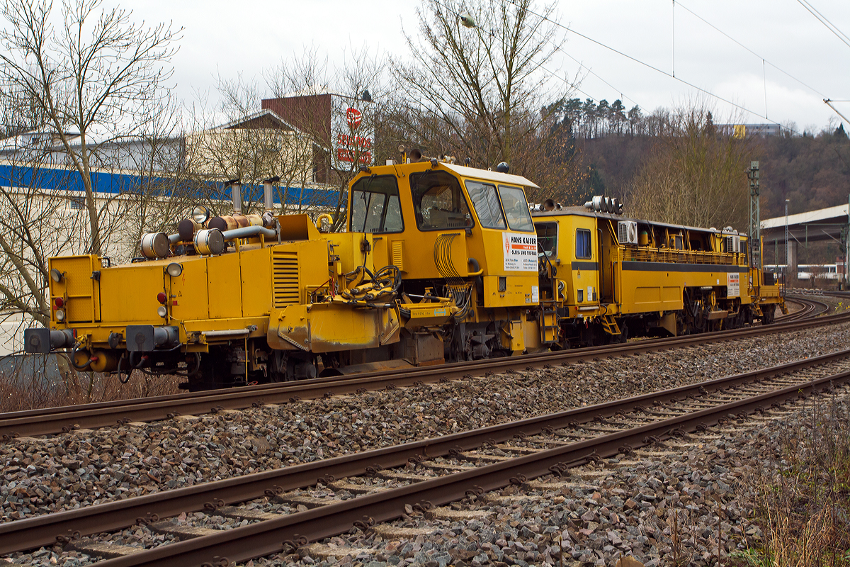 
Die Matisa Schotterplaniermaschine vom Tpy R 20 L (Schweres Nebenfahrzeug Nr. 97 16 38 501 17 – 3) und die Plasser & Theurer Zweischwellenstopfmaschine 09 - 32  CSM (Schweres Nebenfahrzeug Nr. 97 40 68  524 17 -9) beide von der Firma Hans Kaiser GmbH & Co. KG aus Tann stehen am 20.12.2014 auf dem Verbindungsgleis zwischen dem Hbf Siegen und dem KSW Bahnhof Siegen-Eintracht.

Die Schotterplaniermaschine wurde 1993 von MATISA Mat�riel Industriel S.A in Crissier (Schweiz) unter der Fabriknummer 6714 gebaut und an die Th�ringer Gleisbau geliefert.

Die modulare Baureihe R 20 wird bereits seit 1987 hergestellt, wir hier ist es Normalspur-Maschine. Entwickelt wurden diese Maschinen jedoch speziell f�r Schmalspurnetze oder Netze mit begrenzter Achslast entwickelt. Der Schotterpflug der Baureihe R 20 kann in beide Fahrtrichtungen (Richtungsunabh�ngig) arbeiten, dies hat den Vorteil Leerfahrten der Maschine zu vermeiden und Schotterverschiebungen von einer Bettungsschulter zur anderen in einem einzigen Arbeitsdurchgang durchzuf�hren. Daraus ergibt sich ein bemerkenswerter Zeitgewinn, wobei meist das Stopfen den gr��ten Zeitaufwand ben�tigt. Die gro�e Beweglichkeit der Seitenpfl�ge erm�glicht auch bei hohen Geschwindigkeiten das Umgehen von Hindernissen. Die Anpassung an alle Gleisschulterprofile und das Arbeiten im Seitenbereich der Gleise erfolgt ohne Verletzung des Lichtraumprofils des Nachbargleises.

Die vor der Kabine angeordneten Zentralpfl�ge bleiben stets im Sichtbereich des Bedieners. Alle Maschinen sind mit einem doppelten Bedienungspult ausger�stet. Die reichlich dimensionierte Kabine bietet eine ausgezeichnete Sicht auf den Arbeitsbereich und das Gleis.

Die B�rsteneinheit ist mit einem Aufnahmekasten ausger�stet, der den wegschleudernden Schotter aufnimmt und auf ein F�rderband leitet, das ihn entweder seitlich auf die Gleisschultern wirft (Version L) oder in einen Silo bef�rdert (Version LS und LT). 

Technische Daten der  Schotterplaniermaschine R 20 L:
Spurweite: 1.435 mm  (lieferbar 1.000 bis 1.676 mm)
Achsanzahl: 2
Achsabstand: 6.200 mm
L�nge �ber Puffer: 13.690 mm
Eigengewicht: 28,5 t
Anh�ngelast: 20 t
Zur Mitfahrt zugel. Personen: 2
H�chstgeschwindigkeit: 90 km/h
Max. Geschwindigkeit beim Planieren: 12 km/h
Max. Geschwindigkeit beim Kehren: 3 km/h      
Kleinster befahrbarer Kurvenradius:  R 75 m      
Motor:  DEUTZ-Dieselmotor vom Typ F 10 L 413 F      
Motorleistung:  196 kW / 2300 U/min

Beschreibung der P&T Zweischwellenstopfmaschine 09 – 32 CSM siehe: http://hellertal.startbilder.de/bild/Deutschland~Bahndienstfahrzeuge~Schotterplaniermaschinen/392853/die-plasser--theurer-zweischwellenstopfmaschine-09.html