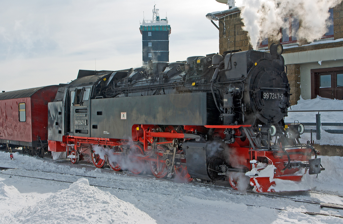 
Die Neubau-Dampflok der Harzer Schmalspurbahnen HSB 99 7247-2 (ex DR 099 157-0, 99 0247-9, 99 247) erreicht am 23.03.2013 den Bahnhof Brocken (1.125 m ü.NN),  welcher sich knapp unterhalb des 1.142m hohen Gipfel des Brocken befindet. 

Die meterspurige Dampflok wurde 1957 bei LKM (VEB Lokomotivbau Karl Marx Babelsberg unter der Fabriknummer 134028 gebaut und als DR 99 247 an die Deutsche Reichsbahn geliefert. Zum 01.07.1970 erfolgte die Umzeichnung in DR 99 7247-2, nachdem man sie 1980 auf Ölfeuerung umbaute wurde sie als DR 99 0247-7 bezeichnet. Da die Ölfeuerung nicht zum Vorteil der Maschinen war und Öl in der DDR knapp war wurde sie (wie alle Loks) 1983 wieder auf Kohlefeuerung zurück gebaut und nun wieder als DR 99 7242-2 bezeichnet. Ab dem 01.01.1992 wurden die Lok noch als DR 099 157-0 um bezeichnet, bis am 01.02.1993 in die HSB überging, welche dann wieder die alte DR-Bezeichnungen verwendete.
