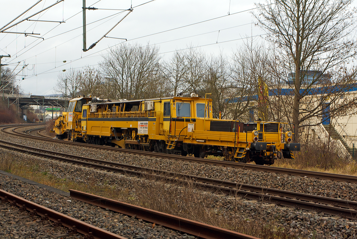 
Die Plasser & Theurer Zweischwellenstopfmaschine 09 - 32  CSM (Schweres Nebenfahrzeug Nr. 97 40 68  524 17 -9) und die Matisa Schotterplaniermaschine vom Tpy R 20 L (Schweres Nebenfahrzeug Nr. 97 16 38 501 17 – 3) beide von der Firma Hans Kaiser GmbH & Co. KG aus Tann stehen am 20.12.2014 auf dem Verbindungsgleis zwischen dem Hbf Siegen und dem KSW Bahnhof Siegen-Eintracht.

Die Stopfmaschine wurde 1993 von Plasser & Theurer unter der Fabriknummer 2618 gebaut und an die Th�ringer Gleisbau GmbH geliefert.

Die 09-32 CSM sind kontinuierlich arbeitende Stopf,- Hebe- und Richtmaschinen. Der kontinuierliche Arbeitsablauf erm�glicht sehr hohe Schichtleistungen. Das Stopfen im Bereich von Weichen ist mit ihr nicht m�glich.

Technische Daten der Stopfmaschine 09 – 32 CSM:
Spurweite: 1.435 mm
Achsanzahl: 6
Drehzapfenabstand: 7.500 / 13.700 mm
L�nge �ber Puffer: 27.700 mm
Eigengewicht: 69t
Anh�ngelast: 40 t
H�chstgeschwindigkeit (bei Eigenfahrt): 90 km/h
H�chstgeschwindigkeit im Zugverband: 100 km/h
Zugelassen zur Mitfahrt:  6 Pers.
Kleinster befahrbarer Kurvenradius:  R 120 m      
Zugelassen f�r Streckenklasse: B1 und h�her
Motor:  DEUTZ-Dieselmotor vom Typ BF12L 513C
Motorleistung: 348 kW

Leistungsparameter:
Hebe- und Verdichtstopfgang: ca. 250-300 m/h
1. Stabilisierung: 450 m/h
2. Stabilisierung: 600-800 m/h
Durcharbeitung (Hbg. bis 25mm): 800 m/h
Max. �berh�hung: 160 mm
Min. Arbeitsradius: 150 m
Die tats�chlich zu erbringende Leistungsmenge je Stunde variiert aufgrund der unterschiedlichen
Randbedingungen (Hebewerte, Gleisgeometrie etc.) der einzelnen Ma�nahmen.

Beschreibung der Matisa Schotterplaniermaschine R 20 L siehe: http://hellertal.startbilder.de/bild/Deutschland~Bahndienstfahrzeuge~Schotterplaniermaschinen/392854/die-matisa-schotterplaniermaschine-vom-tpy-r.html