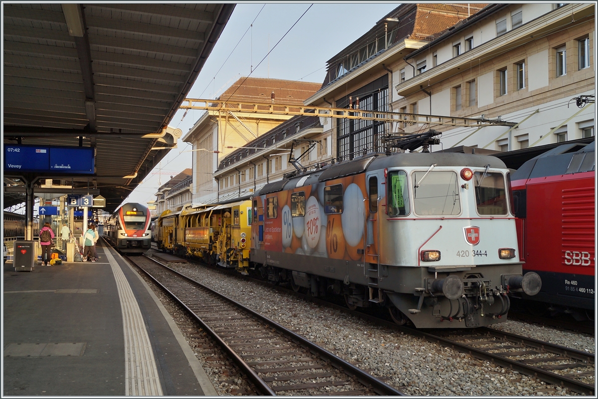 Die SBB Re 4/4 II 11344 (Re 420 344-4 / UIC 91 85 4420 344-4 CH SBBC) mit einer Gleisbaumaschine die auf den Namen  Hummel  h�rt. bzw. mit D-Krebs 99 80 91 24 011-4 beschriftet ist, beim Abwarten auf die Weiterfahrt in Lausanne. 

17. April 2021