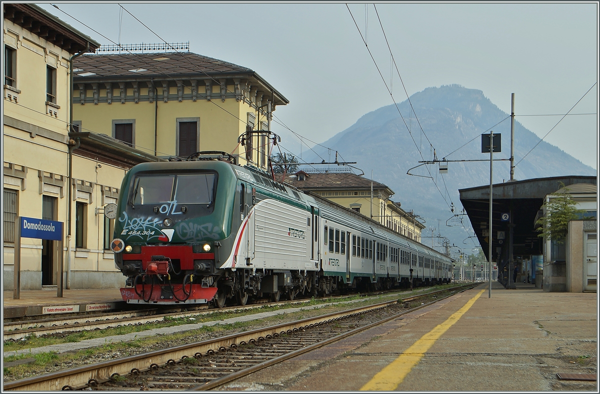 Die  trenord  E 464.304 wartet mit einem Regionalzug in Domodossola auf die Abfahrt Richtung Milano. 
Die Übernahme des Regionalverkers in der Lombardei von wenigen Jahren durch die  trenord  scheint beim Personal einige Spannungen ausgelöst zu haben, denn relativ oft wird hier gestreikt, auch fällt nun auf, dass die  trenord -Fahrzeuge trotz oftmals neuer Farbgebung weniger gepflegt wirken, wie neuerdings jene der FS.
11. April 2015