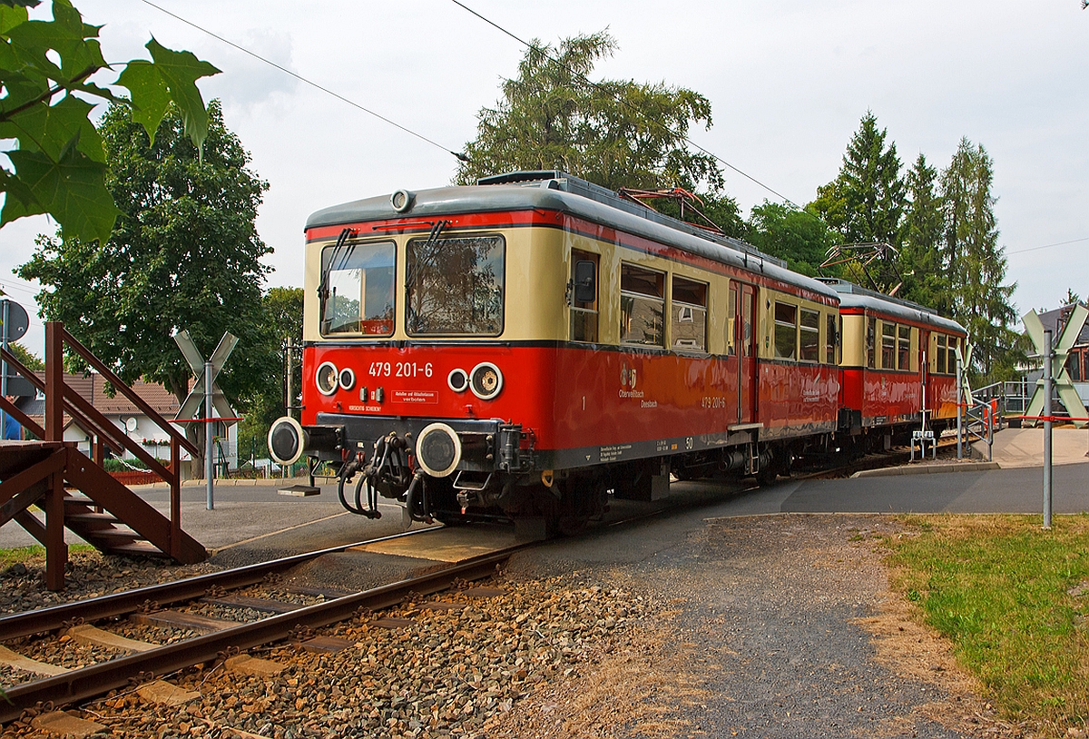 Die Triebwagen der Oberwei�bacher Bergbahn DB 479 201-6 und DB 479 203-2 sind am 24.08.2013 gerade vom Bergbahnhof Lichtenhain  nach Cursdorf losgefahren, diese Triebwagen fahren hier auf der Flachstrecke der KBS 563 zwischen Lichtenhain und Cursdorf. 

Es gibt insgesamt drei dieser Elektro-Triebwagen, es sind die einzigen ihrer Art und werden im Nummernsystem der Deutschen Bahn AG als Baureihe ET 479 bezeichnet. So gleich wie sie  aussehen, ist ihre Herkunft ganz und gar nicht. Jeder von ihnen hat seine eigene, faszinierende Geschichte, die gepr�gt ist von der st�ndigen Geldnot der Bergbahnbetreiber und  wirtschaftlichen Zw�ngen. So kam zu DDR- Zeiten die  Deutschen Reichsbahn als Betreiber in die Situation, unbedingt neue Fahrzeuge beschaffen zu m�ssen. Jedoch gab es nie eine Freigabe f�r solch ein Vorhaben. Also umging man den  Neubau  und beauftragte  Umbauten . Das Reichsbahnausbesserungswerk (Raw) Berlin-Sch�neweide, das diese Triebwagen und Beiwagen betreute und f�r die Instandsetzung der Berliner S-Bahn verantwortlich war, durfte keine Neubauten ausf�hren, jedoch Umbauten (Rekonstruktionen) vornehmen. So entstanden nacheinander drei nahezu identische Fahrzeuge, die ganz  zuf�llig  den S-Bahn-Z�gen der Baureihe 476/477 (ex. 276) �hnlich sind und gleiche Front- und Seitenteile haben, sowie gleiche zweifl�glige Schiebet�ren. 

Vorne DB 479 201-6, ex DRG ET 188 531, ex DR 279 201-8, dieser ist der einzige speziell f�r die Flachstrecke gebaute Triebwagen, er entstand 1922/23 in der Gothaer Waggonfabrik und die Bergmann Elektrizit�tswerke in Berlin lieferten die Elektrik. Das Fahrzeug erhielt 1969 die EDV-Nummer DR 279 201-8. 1970 wurde er grundlegend umgebaut und mit einem neuen Wagenkasten ausger�stet, 1982 nochmal im Raw Sch�neweide umgebaut. Er wird seit 1991 unter der Nummer 479 201-6 gef�hrt. 

Hinten der DB 479 203-2, ex Leipziger Stra�enbahn Nr. 939, ex DR 188 701, ex DR 279 203-4. Dieser Triebwagen wurde 1909 als Stra�enbahntriebwagen 209 df�r die Leipziger Elektrischen Stra�enbahn durch die Waggonfabrik P. Herbrand in K�ln gebaut, die elektrische Ausstattung lieferte AEG in Berlin. Der Wagen wurde im Lauf seiner Betriebszeit viermal grundlegend umgebaut, so dass es nicht sicher ist, ob zuletzt �berhaupt Teile des Ursprungsfahrzeuges vorhanden sind. 
1929/30 wurde er wie alle Triebwagen des Typs 16 in den Typ 27 mit geschlossenen Plattformen umgebaut, bis 1955 war er bei der Leipziger Stra�enbahn. Im  Raw Gotha wurde er dann 1955 f�r den Einsatz auf der Flachstrecke angepasst und u.a. auf Regelspur mit Fernbahnradreifen umgespurt, mit Pufferbohlen und Puffern sowie einem seitlich versetzten Stromabnehmer versehen. Au�erdem erhielt er wieder eine diesmal indirekte Druckluftbremse. Anschlie�end erhielt er die Betriebsnummer ET 188 701. In dieser Form diente er vorwiegend als Reservefahrzeug. 1963 erfolgte der dritte Umbau, diesmal im Raw Berlin-Sch�neweide: Das Fahrzeug erhielt einen neuen, eckigen Wagenkasten mit abgeschr�gten Enden in geschwei�ter Stahlausf�hrung sowie rollengelagerte Rads�tze mit 800mm Laufkreisdurchmesser und einem Achsstand von 5000 Millimetern. Die elektrische Ausr�stung und Steuerung wurde an den ET 188 531 angepasst. Mit der Einf�hrung der EDV-Nummerierung 1969 erhielt er die Nummer 279 203-4. Der letzte Umbau erfolgte dann 1984 im im Raw Sch�neweide.  

Technische Daten f�r ET 479 201 und 203:
Achsfolge:  Bo
Achsstand : 6.500 mm
L�nge �ber Puffer:  11.600 mm
Raddurchmesser:  900 mm
Dienstgewicht:  19,5 t
Bremsgewicht:  15,5 t
Stromsystem:  600 V Gleichstrom
Antrtiebsleistung : 2 x 60 kW Gleichstrom-Reihenschlussmotoren
H�chstgeschwindigkeit:  50 km/h
Sitzpl�tze:  24
Stehpl�tze:  84
Bremsen: 2 Handbremsen, elektrische Widerstandsbremse, Druckluftbremse Bauart Knorr  KpBr , Bremsstellung  P 
Sicherheitsfahrschaltung  Bauart: Sifa 86

Damit die Wagen auf der G�terb�hne nach Lichtenhain auf die Flachstrecke der Oberwei�bacher Bergbahn transportiert werden konnten, erhielten sie deshalb den relativ kurzen Achsstand von 6,5 m.