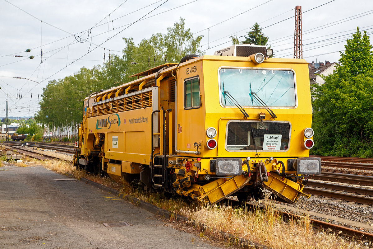 
Die Universal-Stopfmaschine Unimat-Sprinter ESM 866 der DB Netz AG (Schweres Nebenfahrzeug Nr. 97 43 52 006 17-1) steht am 31.05.2019 in Kreuztal. Der Unimat-Sprinter ist eine von Plasser und Theurer entwickelte Stopfmaschine f�r Gleise, Weichen und Kreuzungen, speziell konzipiert f�r die rasche und pr�zise Behebung von Einzelfehlern. Daher auch die Abk�rzung ESM = EinzelfehlerStopfMaschine.

Die Stopfmaschine (ESM – 08 – 275 / Sprinter) wurde 2000 von Plasser & Theurer unter der Fabriknummer 1169 gebaut und an die DB Netz AG geliefert.

Die typische L�nge eines Einzelfehlers betr�gt 9 bis 15 Schwellen, er kann sich in Einzelf�llen aber bis zu 100 m weit erstrecken. Die Ursachen liegen nicht im direkten  Zusammenhang  mit  Nivellier-  und  Richtarbeiten oder Zugbelastungen, sondern vielmehr in punktuellen, scharf   abgegrenzten Schw�chen im Unterbau, Frostsch�den usw.
Da dieser Einzelfehler in einem v�llig intakten Abschnitt liegt,  der keiner durchgehenden Behandlung bedarf, ist es viel zu aufwendig, solche Abschnitte zur G�nze zu bearbeiten. Die Behebung eines Einzelfehlers ist aber unumg�nglich, da nicht  nur Gr�nde wie kostspielige Langsamfahrstellen daf�r sprechen, sondern auch die Sicherheit des Fahrweges garantiert werden muss.

Der UNIMAT SPRINTER ist eine speziell f�r die Einzelfehlerbehebung entwickelte Stopfmaschine. Sie ist mit zwei Weichenstopfaggregaten mit jeweils vier Schwenkpickeln zur universellen Bearbeitung von Strecken und Weichen  ausgestattet. Das kombinierte Hebe- und Richtaggregat besteht aus einem Hebehaken, einer Richtrolle und einer Rollhebezange pro Schienenstrang. F�r eine schnelle �berstellung zur Baustelle ist die Maschine mit einem hydrodynamischen Antrieb f�r eine H�chstgeschwindigkeit von 100 km/h ausgelegt. Flankenpfl�ge, die im Bereich des vorderen Drehgestells montiert sind und eine Kehrb�rste am hinteren Ende der Maschine, sorgen nach den Stopfarbeiten f�r  die Herstellung des geforderten Schotterprofils.

Technische Daten der UNIMAT SPRINTER:
Spurweite: 1.435 mm
Achsanzahl: 4 (in 2 Drehgestellen)
Achsabstand im Drehgestell: 1.500 mm
Lauf- und Treibraddurchmesser: 730 mm (neu)
Drehzapfenabstand: 10.500 mm
L�nge �ber Puffer: 18.140 mm
Eigengewicht: 54t
Anh�ngelast: 40 t
H�chstgeschwindigkeit: 100 km/h
Zugelassen zur Mitfahrt: 4 Pers.
Kleinster befahrbarer Kurvenradius:  R 90 m      
Zugelassen f�r Streckenklasse: A und h�her