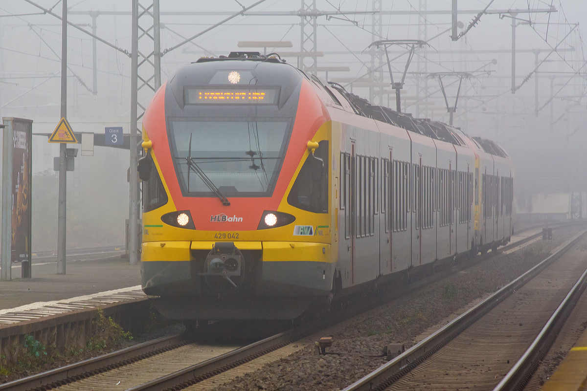 
Durch den Nebel in der Wetterau....
Der 5-teilige Stadler Flirt 429 042 / 542 gekoppelt mit dem 3-teiligen Stadler Flirt 427 543 / 427 043 der HLB Bahn (Hessischen Landesbahn) fahren am 01.11.2014, als RE 99 / RE 40 Siegen - Gießen - Frankfurt Hbf (Umlauf HLB24957), durch den Bahnhof Butzbach in Richtung Frankfurt am Main. 
Die Linie verkehrt in NRW als RE 99 und im Gebiet des Rhein-Main-Verkehrsverbundes in Hessen als RE 40.