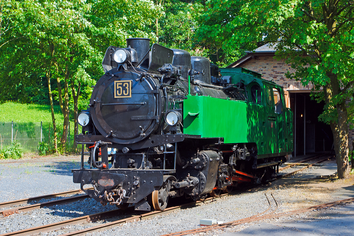 Ehemalige Schmalspur-Dampflokomotive Nr. 53 der Rhein-Sieg Eisenbahn (RSE) am 08.06.2014 im Museum Asbach (Ww). 

Bei dieser Tenderdampflokomotive handelt es sich um die größte, schwerste und leistungsfähigste ehemalige Lok der Rhein-Sieg Eisenbahn (RSE), gleichzeitig ist sie eine der modernsten Schmalspurdampfloks Deutschlands.

Die Lok wurde 1944 unter Fabriknummer 10175 von der Firma Jung in Jungenthal bei Kirchen/Sieg gebaut. 

Technische Daten:
Hersteller:  Lokomotivfabrik Jung/Jungenthal bei Kirchen/Sieg
Fabriknummer:  10175
Baujahr: 1944
Spurweite: 785 mm
Bauart:  1'D1' h2t
Baujahr: 1944
Leergewicht: 40,5 Tonnen
Dienstgewicht: 51 Tonnen
Wasser: 4,6 m³
Kohle: 2,0 Tonnen
Länge über Puffer: 11.345 mm
Breite:  2.260 mm
Höhe ü. SO:  3.370 mm
Höchstgeschwindigkeit: 50 km/h
max. Kesselüberdruck:  15 bar
Rostfläche:  2,0 m²

Ausrüstung:
Heusinger-Steuerung, Schieber Bauart Karl-Schulz, Antrieb auf 4. Kuppelachse, 1 und 4 Kuppelachse gebremst, 2. + 3. Kuppelachse um ± 25 mm seitenbeweglich; Nachlaufachse mit Außenrahmen und Zug- / Stoßeinrichtungen, Laufachsen als Bisselachsen, vorn ± 150 mm, hinten ± 200 mm; genieteter Kessel mit Stahlfeuerbüchse, Wagner-Heißdampfregler, genieteter Blechrahmen, 21,8 % ausgeglichene Massen, Strube Dampfstrahlpumpe (125 l/min), S.H.G. Abdampfstrahlpumpe (52/86 l/min), Einkammer-Druckluftbremse Bauart Knorr mit Zusatzbremse und Handhebelbremse, zweistufige Luftpumpe, Druckluftsandstreuer, Dampfheizung-Anschluß, Lichtmaschine

Geschichte:
Für den steigenden Basaltverkehr aus den Brüchen des Westerwalds zu den Reichsbahn-Übergabebahnhöfen Hennef und Siegburg und zum Rheinhafen in Beuel benötigte die RSE Ende der dreißiger Jahre neue Lokomotiven. Die C-Kuppler von Jung und O&K aus Zeit der Jahrhundertwende waren zu klein und veraltet, die drei Jung-D-Kuppler wurden für Rollwagenzüge benötigt, und die vier 1'D1'-Tenderloks aus den zwanziger Jahren (Jung und Borsig) reichten allein nicht aus.

So bestellte die Direktion 1939 bei der Lokfabrik Jung/Jungenthal zwei Neubaudampfloks, die den großen Verkehrsbedürfnissen entsprechend völlig neu konstruiert wurden und die Nummern 53 und 54 tragen sollten. Während der Zeit des zweiten Weltkriegs konnte eine solche Bestellung nur mit kriegswichtigen Transportgütern begründet werden, die sich bei der RSE in Form von Basalt für den Bau von Befestigungen und in U-Boot-Batterien der Bleihütte Luise (Krautscheid) fanden. Um die für den Bau benötigten Metallkontingente genehmigt zu bekommen, mußten erst einmal 60 Tonnen Schrott für 40 Tonnen Lokgewicht gesammelt werden. Die Kriegsereignisse behinderten den Bau so sehr, daß man zunächst nur eine Lok in Angriff nahm. Bereits 1943 erfolgte die Druckprobe des Kessels, aber die Fertigstellung der gesamten Lok verzögerte sich bis 1944. Am 12. Juni 1944 kam sie in Hennef an, aber erst am 31. Januar 1945 konnte die erfolgreiche Probefahrt nach Waldbröl und Asbach durchgeführt werden, die Abnahme erfolgte zwei Tage später.

Die 53 kam sofort in den Betriebsdienst und geriet während einer Fahrt durch das Bröltal im März '45 unter Tieffliegerbeschluß. Nur der Geistesgegenwart des Personals war zu verdanken, daß keine großen Schäden oder sogar Totalzerstörung eintraten. Die Einschußstellen sind noch heute sichtbar!

Nach Ende der Kampfhandlungen und langsamer Wiederaufnahme des Bahnbetriebs mit den üblichen Einschränkungen wurde die Lok bei ihrem Hersteller Jung repariert und kam mehr schlecht als recht wieder ans laufen. Die kriegsbedingte Verwendung minderwertiger Materialien zeigte nun Folgen, vor allem die stählerne Feuerbüchse bereitete viele Probleme. Die Jahre 1951 bis 1954 verbrachte sie im Herstellerwerk, erst nach Austausch der Feuerbüchse gegen eine solche aus Kupfer zeigte die 53 allgemein befriedigende Leistungen. Aber sie hatte Macken und war nicht leicht zu handhaben, weshalb nur ausgesuchte Lokführer mit ihr fahren durften, die sehr stolz auf ihre prächtige Maschine waren. 

1957 erfolgte in der Hennefer Werkstatt ein Umbau zum Betrieb mit Ölfeuerung, welche sich zuvor bei Lok 32 sehr bewährt hatte. Im Gegensatz zur DB, die für ihre später umgebauten Ölloks das zähe Bunkeröl C verwendete, benutzte die RSE das leichtere B-Öl. So entfiel die Notwendigkeit einer ständigen Ölheizung, mit der zähe Öle fließfähig gemacht werden müssen. Nun konnte auch der Heizer eingespart werden, die Bedienung des Kessels hatte der Lokführer mit zu verantworten. Bei Streckenfahrten fuhr nun der Zugführer zwecks Streckenbeobachtung im Führerstand mit, wodurch auch die Mitnahme des Packwagens entfallen konnte.

Zur noch rationelleren Betriebsdurchführung beschaffte die RSE 1959/60 drei Dieselloks vom O&K-Typ MV8 mit je 130 PS Leistung. Die anfällige 53 kam immer seltener zum Einsatz, ihre letzte Fahrt ist für den 17.8.1966 verbürgt. Zuvor war sie längere Zeit arbeitslos, die letzten regulären Einsätze fanden an neun Tagen im November 1965 statt. Ein letztes Probeheizen führte das Personal am 16.8.66 durch, am nächsten Tag bewegte sich die Lok zum letzten Mal aus eigener Kraft.

Weitere Informationen: http://www.museum-asbach.de/index.html
Das kleine Museum ist einen Abstecher wert, leider ist es nur einmal im Monat offen. Der Eintritt ist freiwillig, aber man sollte immer bedenken welch Aufwand für den erhalt der Loks erforderlich ist.