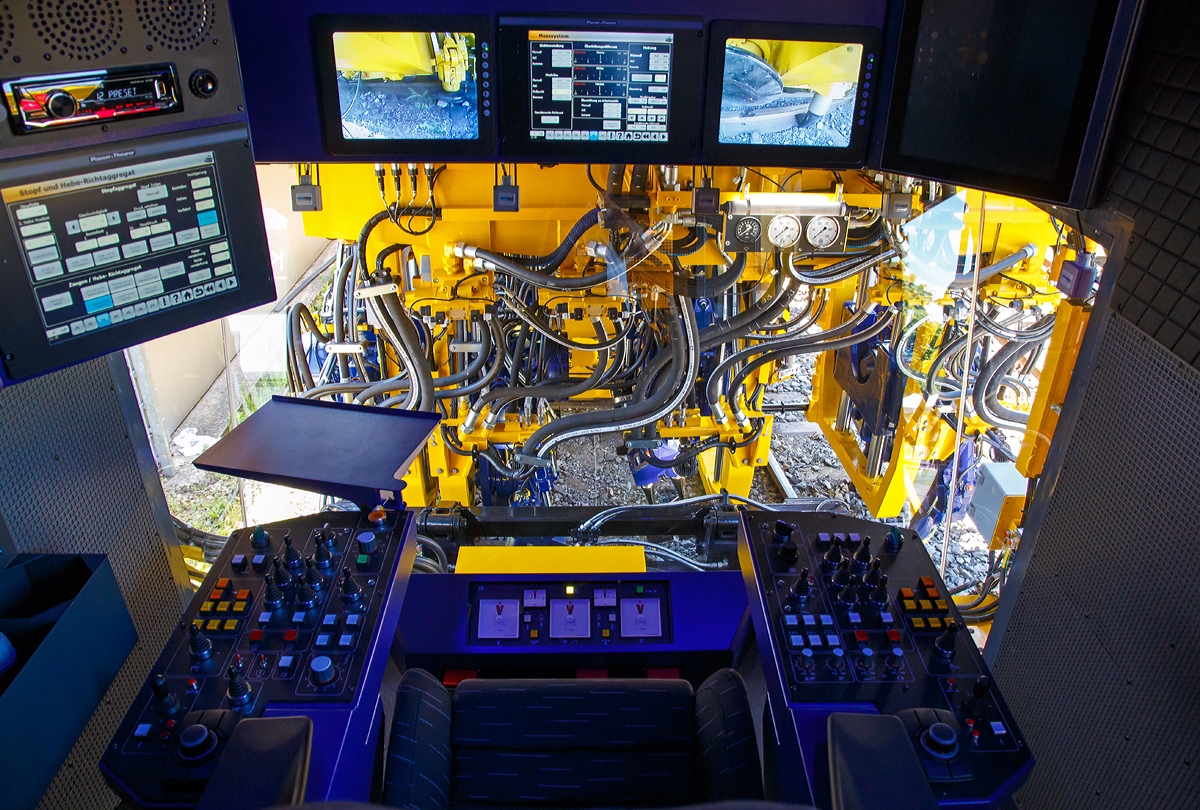 
Ein Blick in und aus der Maschinenführerkabine der Plasser & Theurer  UNIMAT 09-4x4/4S E3 ATW (A-PLA 99 81 9124 004-8),  eine Universal-Weichenstopfmaschine mit Hybrid-Antriebstechnik, der Franz Plasser Vermietung von Bahnbaumaschinen GmbH präsentiert auf der iaf 2017 in Münster (am 01.06.2017). Es gint sehr viele Könpfe und Schalter, aber auch Anzeigen sowie Videobildschirme.