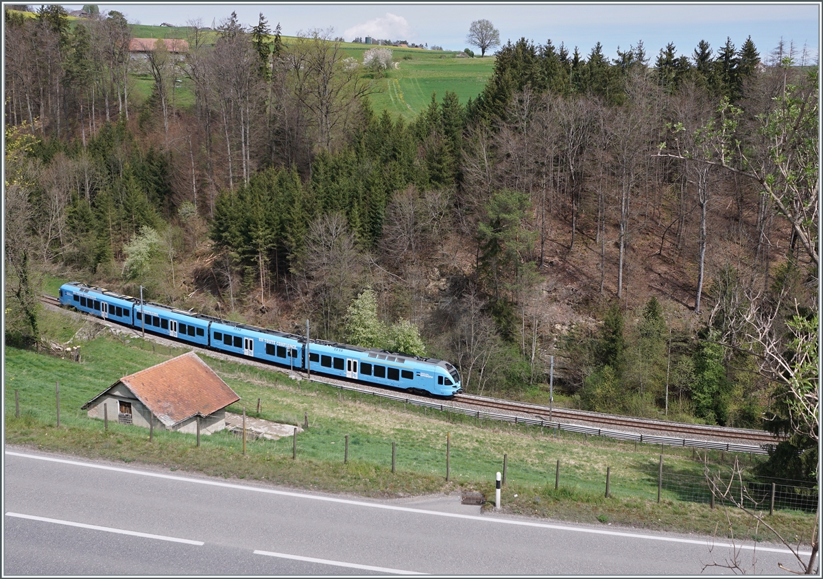 Ein Einblick in den Einschnitt des Streckenabschnittes Courtepin - Pensier von einer etwas höher gelegen Position aus, welche einen Blick auf die dahinter liegende Landschaft gewährt. Im Bild der im sehr gefälligen Werbeanstrich der  Groupe Grisoni  gehaltene TPF RABe 527 198 welcher sich als RER 21 14649 auf der Fahrt von Ins nach Fribourg befindet. 

19. April 2022