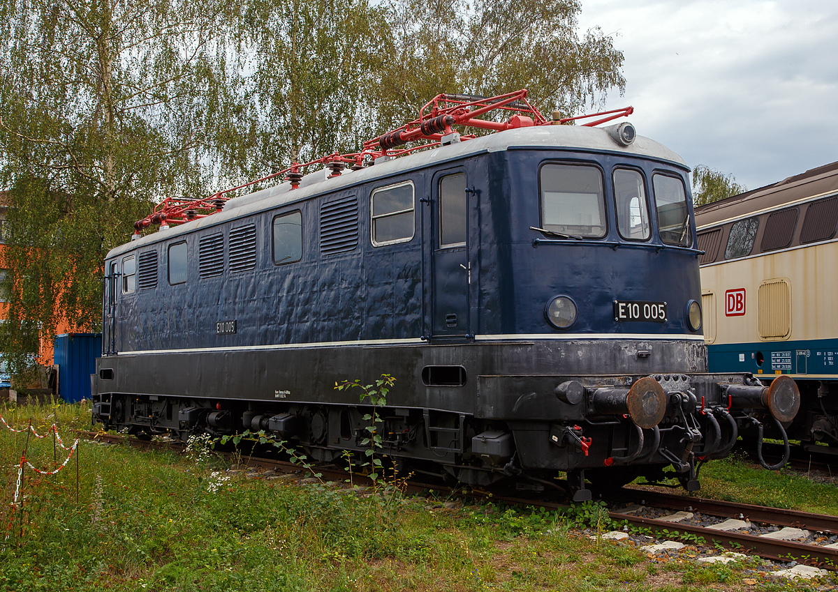 Eine ungewohnte E 10:
Die E 10 005, später 110 005–6, steht am 04.09.2020 im DB Museum Koblenz-Lützel. Diese fünfte Vorserien E 10 wurde 1953 von Henschel & Sohn in Kassel unter der Fabriknummer 28467 gebaut, die Elektrik wurde von AEG unter der Fabriknummer 7174 geliefert.  Zum 30.08.1979, nach einer Laufleistung von 4,34 Mio. km, erfolgte die Ausmusterung bei der DB und 1980 wurde sie zur Museumslok.

Die Vorserienlokomotiven wurden weitgehend von der Industrie entwickelt, wobei verschiedene Komponenten ausprobiert wurden:
Die E 10 001 stammt im mechanischen Teil von Krauss-Maffei und im elektrischen Teil von AEG. Sie besaß einen Alsthom-Gelenkhebelantrieb.
Die E 10 002 stammt mechanisch von Krupp und elektrisch von BBC und hatte einen BBC-Scheibenantrieb.
Die E 10 003 kam von Henschel und SSW und hatte einen SSW-Gummiringfederantrieb.
Die E 10 004 lieferten Henschel und AEG und sie wurde durch einen Sécheron-Lamellenantrieb angetrieben. Baugleich mit ihr war die E 10 005, die 1953 nachgeliefert wurde, um die Lokomotiven auch im täglichen Betrieb testen zu können.

Die neuen Lokomotiven sollten Schnellzüge mit 700 t auf 10 ‰ mit 90 km/h und Güterzüge mit 1300 t auf 5 ‰ mit 70 km/h befördern können. Die Höchstgeschwindigkeit war mit 125 km/h angesetzt. Eine Zugkraft von 7 t am Radumfang war gefordert, wobei 6 t bereits 5 Sekunden nach dem Anfahren aus dem Stillstand erreicht werden mussten. Die Erwärmung der Fahrmotoren durfte 90 Grad nicht überschreiten. Auch durften Schwankungen bei der Fahrdrahtspannung zwischen 10,5 und 18,5 kV keine Betriebsstörungen verursachen. Die Loks sollten zweiachsige Drehgestelle mit Drehzapfen erhalten, wobei die Zugkraftübertragung über den Brückenrahmen und nicht mehr über die Drehgestelle (wie bei der E 44) erfolgen sollte. Auf Vorbauten, wie sie bei den Vorkriegselloks aus Sicherheitsgründen zu finden waren, glaubte man verzichten zu können. Schließlich war Vielfachsteuerung für den Einsatz in Doppeltraktion sowie die Ausrüstung für den Wendezugeinsatz einzubauen. 

Gegenüber den Vorplanungen wurde die Höchstgeschwindigkeit auf 130 km/h heraufgesetzt und die Baureihenbezeichnung in E 10 umgewandelt. Entsprechend dem Schweizer Vorbild waren es Drehgestell-Lokomotiven mit einzeln angetriebenen Achsen jedoch mit unterschiedlichen Antrieben.

Die Auslieferung der Loks erfolgte im Zeitraum zwischen dem 23. August 1952 (E 10 001) und dem 23. März 1953 (E 10 005).

Die E 10-VorserienIoks sollten dazu dienen, möglichst viele neue Bauteile auf ihre Verwendbarkeit für die künftigen Serienloks zu testen. Deshalb unterschieden sie sich weitgehend voneinander und von den folgenden Serienloks.
Einige Bauteile waren jedoch im Prinzip gleich aufgebaut und nur in der Ausführung etwas verschieden. Dazu gehörte der Brückenrahmen, der bei allen Loks aus kastenförmig zusammengeschweißten Stahlblechen bestand. Er setzte sich jeweils aus zwei Längsträgern, zwei Kopfstücken, drei Querträgern (für die Drehzapfen und den Trafo) sowie Deckblechen zusammen und musste die Zug- und Stoßkräfte aufnehmen.
Auch der Kastenaufbau war bei allen Vorserienloks ähnlich konstruiert. Er bestand jeweils aus einem selbsttragenden Gerippe von Stahlprofilen, die auf den Brückenrahmen geschweißt waren und durch angeschweißte Mantelbleche verkleidet wurden. 

Die fünf Vorserien-Lokomotiven der Baureihe E 10.0 wurden zwischen 1975 und 1979 ausgemustert. Erhalten sind die Museumslokomotiven E 10 002 und E 10 005.

TECHNISCHE DATEN der E10 004 und 005:
Spurweite: 1.435 mm
Achsanordnung:   Bo´Bo´   
Länge über Puffer:  15.900 mm 
Treibraddurchmesser: 1.250 mm (neu)
Dienstgewicht:  80 t   
Achslast: 20 t   
Höchstgeschwindigkeit :  130 Km/h
Anfahrzugkraft: 255 kN
Dauerzugkraft: 118 kN
Nennleistung:  3.440 kW
Anzahl Fahrmotoren  4   
Stromsystem:  Einphasen-Wechselstrom 15 000 V, 16 2/3 Hz 