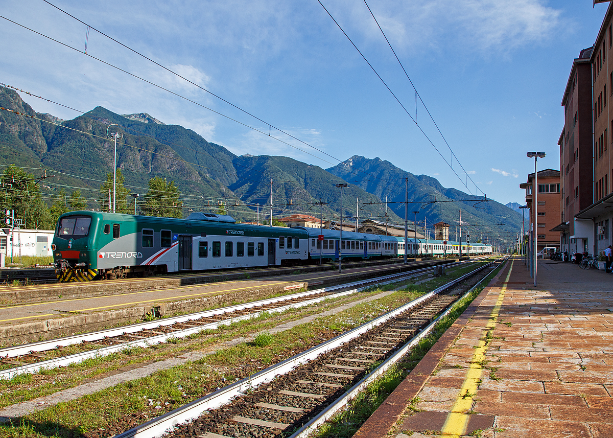 Geführt von einem 2. Klasse Nahverkehrs-Niederflur- Steuerwagen mit Gepäckabteil der Gattung npBDH-Clim erreicht ein langer Trenord-Regionalzug von Mailand (Milano) kommend den Ziel Bahnhof Domodossola. Schublok war einen E.464 (Bombardier TRAXX P160 DCP).