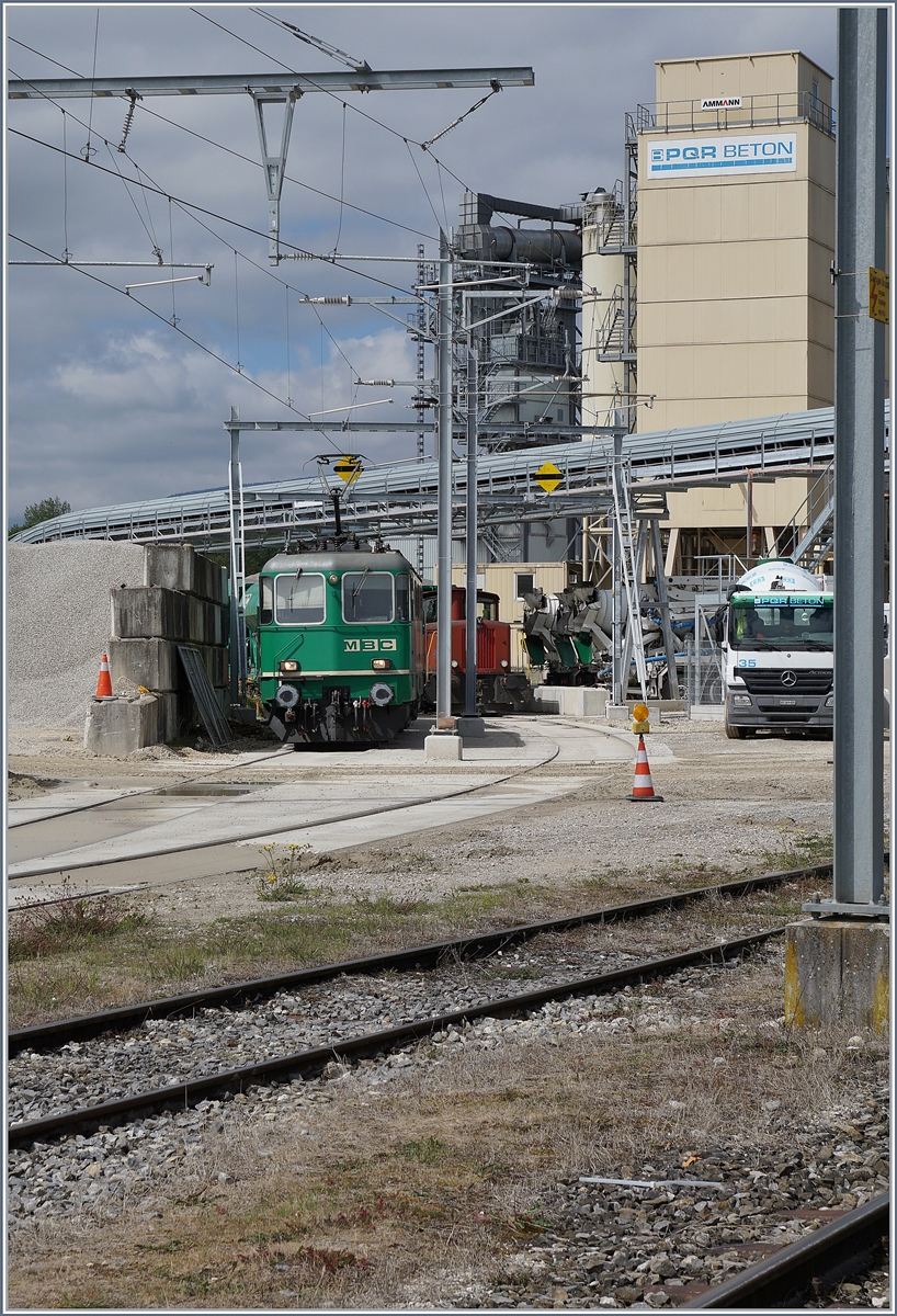 Hier also wird der Kies von Apples weiterverarbeitet: Bei Ballastière in Gland. Die BAM MBC Re 4/4 II (UIC 91 85 4420 506 8 CH MBC) hat bereits die Leerwagengarnitur übernommen und wartet auf die Rückfahrt in den Bahnhof von Gland. Die Fotostelle ist öffentlich zugänglich, erst ein paar Meter weiter verbietet ein Schild den Zugang auf das dort beginnende Betriebsgelände. 
9. Mai 2017