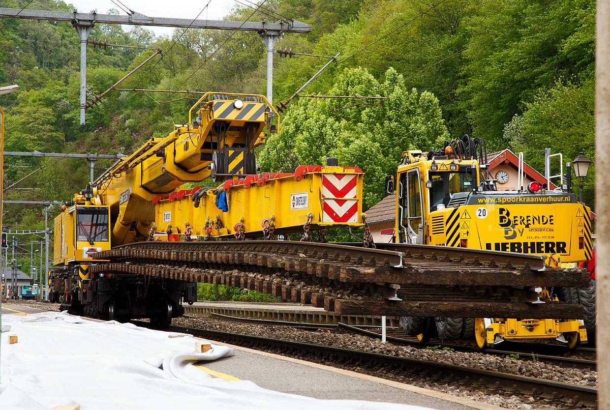 
Ich konnte ein etwas anders Bild von ihm machen....
Der 150 t Kirow Gleis- und Weichenbaukran KRC 1200 (ein Kirow MULTI TASKER KRC 1200) A-RTS 99 81 9119 004-5, ex SKL X 980 009-5, der Firma Swietelsky (eigestellt durch die Tochtergesellschaft RTS Rail Transport Service GmbH) hat die 50 t-Traverse (Eigengewicht 5600) im Hacken, an dieser befinden sich 2 alte Gleisstücke, die er am 14.05.2016 im Bahnhofsbereich von Kautenbach zum Ablageplatz transportiert und absetzt.

TECHNISCHE DATEN von dem Kran:
Spurweite: 1.435 mm
Achsfolge: 1'A'1A'A1'A1'
Eigengewicht  (in Transportstellung) : 128,0 t  (ohne Gegengewichte)
Länge über Puffer:  15.000 mm  (+13.000 mm Gegenlastwagen)
Motorleistung:  254 kW bei 2.200 U/min
max. Geschwindigkeit im Zugverband: 120 km/h
max. Geschwindigkeit im Eigenantrieb: 19 km/h
Achsanzahl:  8 (in 4 Drehgestelle bzw. 2 Doppeldrehgestelle)
Drehzapfenabstand: 10.000 mm
Drehzapfenabstand im Drehgestell 1 und 2: 2.300 mm
Achsabstand in den Einzeldrehgestellen: 1.100mm
Ergebene Achsabstände in m: 1,1 / 1,2 / 1,1/ 6,6 / 1,1 / 1,2 / 1,1
Radsatzlast Gegengewichtswagen:  max. 20,0 t
Höhe in Transportstellung:  4.300 mm
Breite in Transportstellung:  3.100 mm
max. Ausladung vor Puffer:  21.000 mm
max. Traglast bei max. Ausladung:  40 t
Größte mögliche Traglast: 150 t (abgestützt)  / 120t (freistehend)
max. Hakenhöhe:  24.000 mm
hintere Ausladung (Gegenwicht):  7,9 m–13,5 m
Zul. Anhängelast: 150 t
Kleinster befahrbarer Radius: 90 m (120 m im Schleppbetrieb)
Kraftstofftank: 800 Liter (Diesel)

Besondere Ausstattung:
Überhöhenausgleich 180 mm
Schwenkradius ± 360º
Abstützung teleskopierbar bis 8 m Abstützbasis
profilfreies Arbeiten bis ± 30º

Der Kran wurde 2002 von Kirow in Leipzig unter der Fabriknummer 114700 gebaut. 
