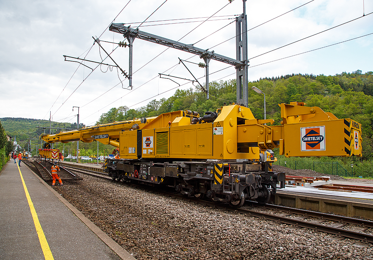 
Ich konnte ein etwas anders Bild von ihm machen....
Der 150 t Kirow Gleis- und Weichenbaukran KRC 1200 (ein Kirow MULTI TASKER KRC 1200) A-RTS 99 81 9119 004-5, ex SKL X 980 009-5, der Firma Swietelsky (eigestellt durch die Tochtergesellschaft RTS Rail Transport Service GmbH) hat die 50 t-Traverse (Eigengewicht 5600) im Hacken, an dieser befindet sich ein alte Gleisstück und wird am 14.05.2016 im Bahnhofsbereich von Kautenbach aus dem Schotter gehoben.

TECHNISCHE DATEN von dem Kran:
Spurweite: 1.435 mm
Achsfolge: 1'A'1A'A1'A1'
Eigengewicht  (in Transportstellung) : 128,0 t  (ohne Gegengewichte)
Länge über Puffer:  15.000 mm  (+13.000 mm Gegenlastwagen)
Motorleistung:  254 kW bei 2.200 U/min
max. Geschwindigkeit im Zugverband: 120 km/h
max. Geschwindigkeit im Eigenantrieb: 19 km/h
Achsanzahl:  8 (in 4 Drehgestelle bzw. 2 Doppeldrehgestelle)
Drehzapfenabstand: 10.000 mm
Drehzapfenabstand im Drehgestell 1 und 2: 2.300 mm
Achsabstand in den Einzeldrehgestellen: 1.100mm
Ergebene Achsabstände in m: 1,1 / 1,2 / 1,1/ 6,6 / 1,1 / 1,2 / 1,1
Radsatzlast Gegengewichtswagen:  max. 20,0 t
Höhe in Transportstellung:  4.300 mm
Breite in Transportstellung:  3.100 mm
max. Ausladung vor Puffer:  21.000 mm
max. Traglast bei max. Ausladung:  40 t
Größte mögliche Traglast: 150 t (abgestützt)  / 120t (freistehend)
max. Hakenhöhe:  24.000 mm
hintere Ausladung (Gegenwicht):  7,9 m–13,5 m
Zul. Anhängelast: 150 t
Kleinster befahrbarer Radius: 90 m (120 m im Schleppbetrieb)
Kraftstofftank: 800 Liter (Diesel)

Besondere Ausstattung:
Überhöhenausgleich 180 mm
Schwenkradius ± 360º
Abstützung teleskopierbar bis 8 m Abstützbasis
profilfreies Arbeiten bis ± 30º

Der Kran wurde 2002 von Kirow in Leipzig unter der Fabriknummer 114700 gebaut. 