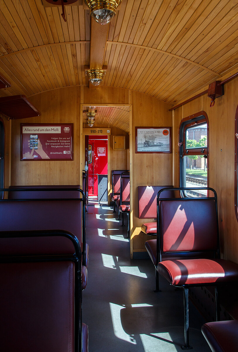 Innenraum von dem Schmalspur (900 mm) vierachsigen 2.Klasse Personenwagen mit offenen Plattformen und Holzdach, MBB 990-310 (ex DR 990-310), der Gattung KB4i, Mecklenburgische Bäderbahn Molli GmbH & Co. (Molli), hier am 15.05.2022 im Bahnhof Ostseebad Kühlungsborn-West.

Der Wagen wurde 1926 von der Waggonfabrik Wismar für die Deutsche Reichsbahn Gesellschaft (DRG) gebaut und ist seitdem bei der Mecklenburgische Bäderbahn im Einsatz. 1980 wurde der Wagen rekonstruiert und erhielt sein heutiges Aussehen. Im Fuhrpark des Molli befinden sich insgesamt 19 Personenwagen.