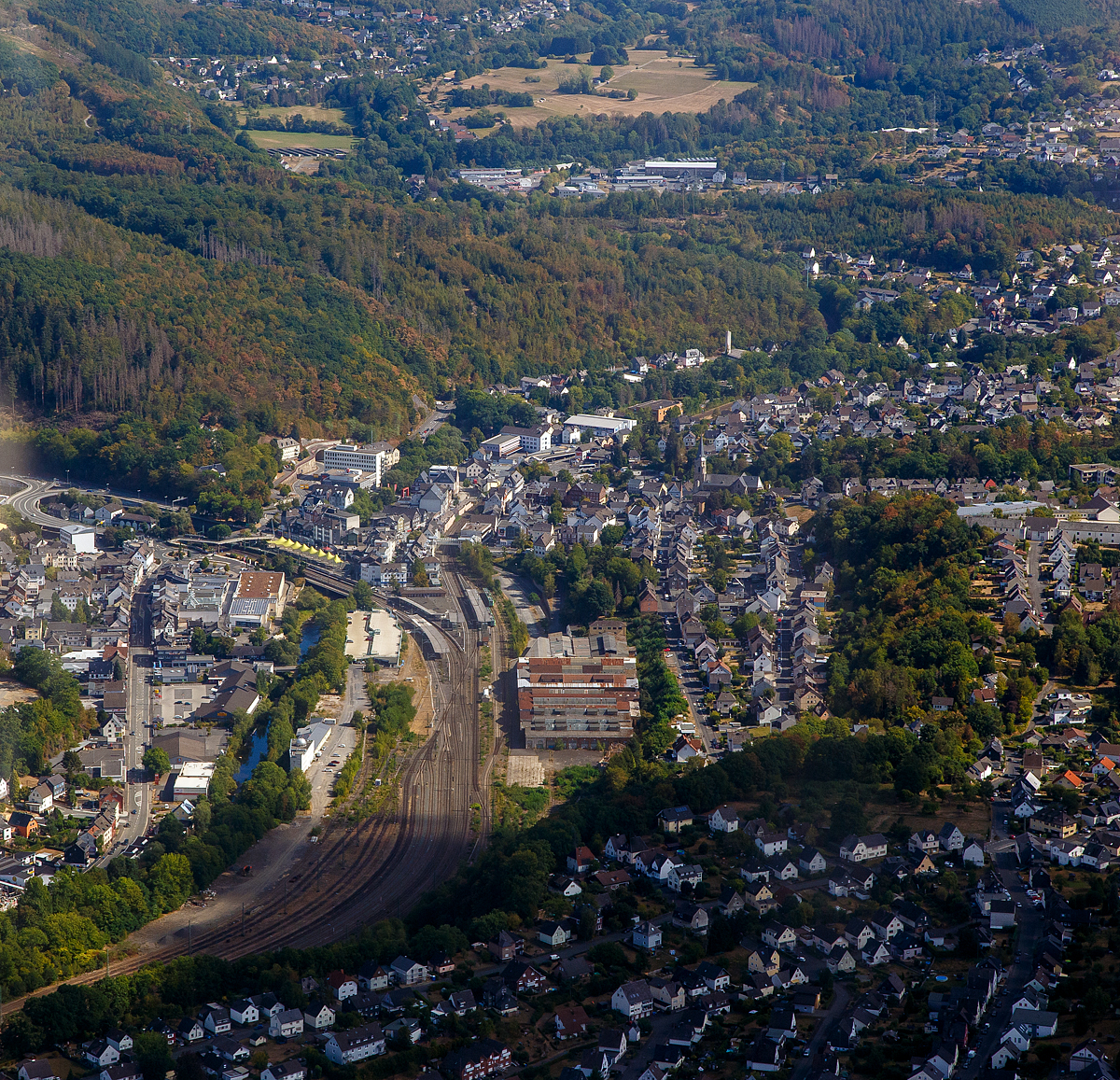 Luftbild vom Bahnhof Betzdorf/Sieg am 04.09.2022, Blickrichtung Osten .
Der Bahnhof Betzdorf (Sieg) besitzt 5 Bahnsteiggleise. Er liegt an Streckenkilometer 83,0 der ehem. Deutz-Gießener Eisenbahn (heute Hellertalbahn) bzw. 123,1 der Siegstrecke und ist Ausgangspunkt der Hellertalbahn nach Haiger/Dillenburg (sowie der Daadetalbahn nach Daaden.

Bis 1915 war die Deutz-Gießener Eisenbahn (heute Hellertalbahn), die eigentliche Hauptstrecke Deutz-Gießener Eisenbahn und die (nach links) abzweigende Bahn von Betzdorf nach Siegen die Nebenstrecke. Durch die Inbetriebnahme der direkten Strecke zwischen Siegen und Haiger und Eröffnung vom Rudersdorfer Tunnel im Jahr 1915 verlagerte sich der Verkehr, Siegen wurde nun zum neuen Knotenpunkt.

Bis zum Niedergang des Siegerländer Erzbergbaus Mitte der 1960er Jahre blieb die Deutz-Gießener Eisenbahn (Hellertalbahn) noch Hauptbahn, bis sie dann als Nebenstrecke zurückgestuft wurde. Die Sieg- und die Ruhr-Sieg- sowie der Dillstrecke wurden 1960er Jahre alle elektrifiziert, die Hellertalbahn nicht.

Rechts das ehemalige AW Betzdorf (Sieg), zu Reichsbahnzeiten auch Eisenbahnausbesserungswerk (EAW). In den letzten Jahren waren die Hallen noch an einen großen Büromöbel und Lagerkästen Hersteller der Region vermietet. Bald soll es noch Plänen der Stadt, zu Betzdorfs neuen Mittelpunkt der Stadt werden. Auf dem ca. 10.000 m² großen Areal sollen Wohnungen, Einkaufmöglichkeiten und Arbeitsplätze entstehen. So steht wohl bald diesen Gebäuden auch der Abriss bevor. 

