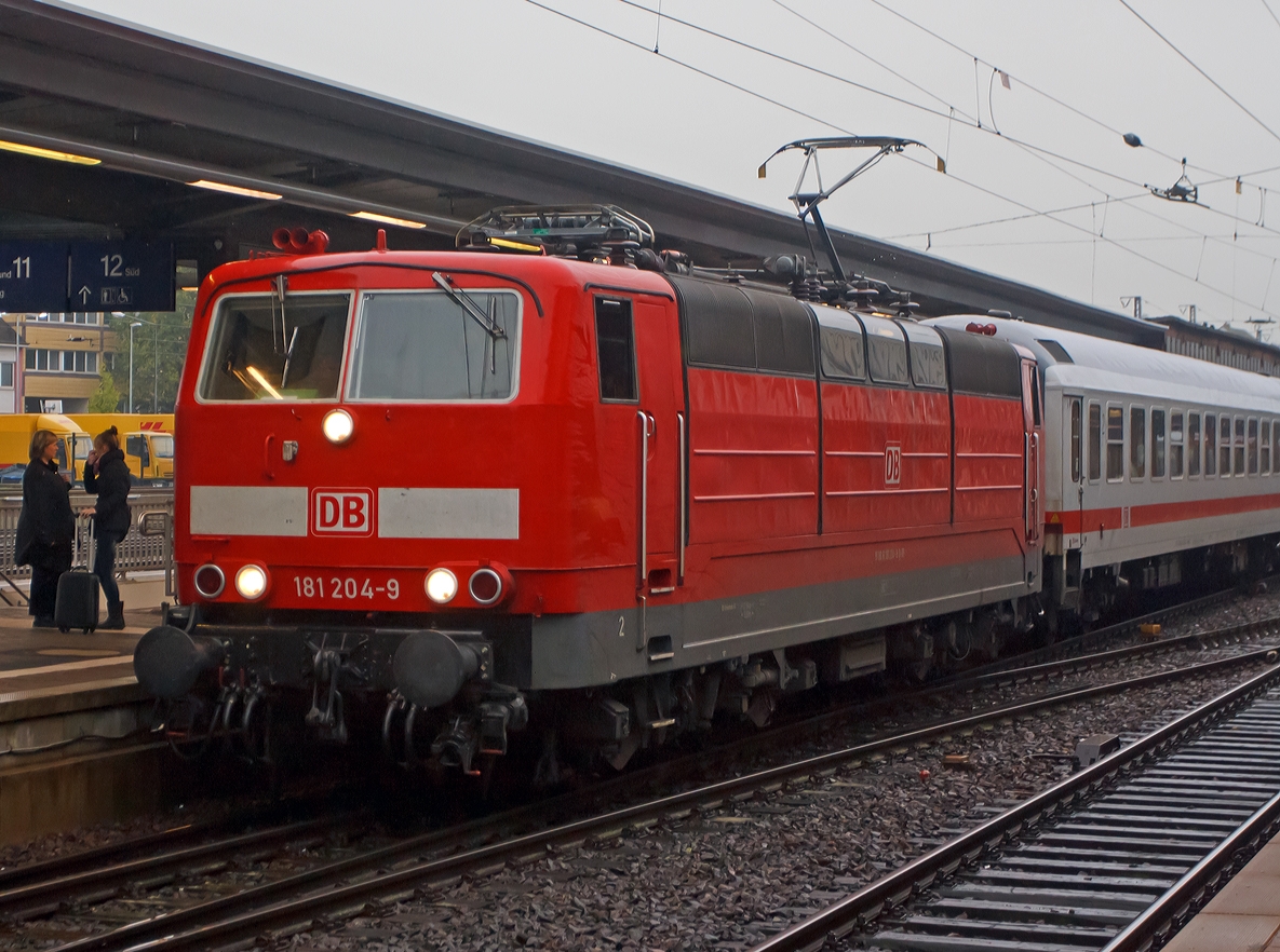 Mit Zehnmen�tiger Versp�tung f�hrt um 9:17 bei Regen die 181 204-9 mit dem IC 133  Ostfriesland  (Luxembourg - Trier - Koblenz - K�ln - Norddeich Mole) in den Hbf Trier ein.  

Noch entlang der Mosel wird der IC bis Koblenz von dieser Zweisystemlokomotive gezogen, in Koblenz wird dann am anderen Zugende dann meist eine 101er angehangen, die den IC dann bis  Norddeich Mole zieht.
Die 181.2er bleiben dann, f�r anderen Gegenzug, in Koblenz stehen. 

Von der Lokbaureihe 181.2 wurde 1974 bis 1975 insgesamt 25 Maschinen speziell f�r den grenz�berschreitenden Verkehr nach Frankreich und Luxemburg beschafft. Diese wurden von Krupp (Mechanischer Teil) und AEG (Elektrischer Teil) gebaut und geliefert. Zudem waren bereit 1966 vier Vorserienlok E 310 (BR 181.0 und 181.1) von Krupp und AEG gebaut worden.

