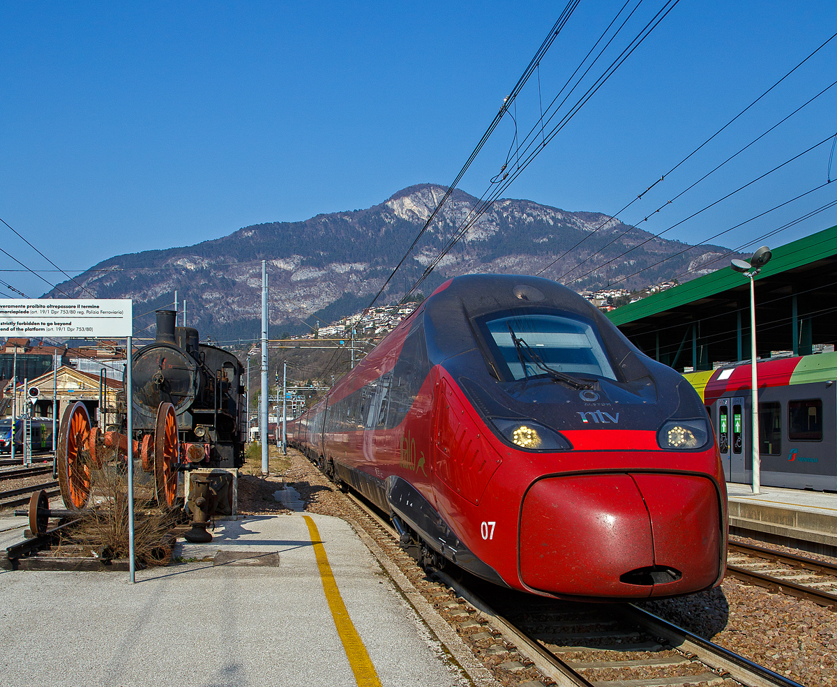 Moderne trieft Geschichte.....
Der NTV ETR 675 bzw. Italo EVO von Bozen nach Rom (Bolzano/Bozen – Trento – Verona – Bologna – Firenze (Florenz) - Roma (Rom) Termini) erreicht am 26.03.2022 den Bahnhof Trento/Trient. Einen lieben Gruß an den netten Lokführer zurück. Links steht die Denkmallok FS 625.011.

Beim Italo EVO (Alstom NTV ETR 675)  handelt es sich um eine Weiterentwicklung des ETR 600, ebenfalls von Alstom, die zur fünften Generation der der Pendolino-Serie. Diese Züge der NTV (Nuovo Trasporto Viaggiatori )wurden unter der Baureihenbezeichnung ETR 675 (ETR von italienisch ElettroTreno Rapido) eingereiht. Anders als der Name der Serie vermuten lässt, verfügen sie nicht über Neigetechnik. Die Züge sind 187 Meter lang und bieten in 7 Wagen 472 Fahrgästen Platz. Die Höchstgeschwindigkeit beträgt 250 km/h. Die ersten 4 dieser Züge wurden im Dezember 2017 eingesetzt, bis 2018 wurden 22 Exemplare angeschafft. Im Jahr 2021 folgte eine Bestellung über vier weitere Triebzüge, dadurch steigt die Gesamtzahl auf 26 Züge.

Die auf der vierten Pendolino-Generation basierenden Triebzüge sind nach aktuellen TSI-Richtlinien konzipiert und können unter 25 kV Wechsel- sowie 3 kV Gleichspannung eingesetzt werden. Sie sind mit vier Einholmstromabnehmern des Herstellers Schunk ausgestattet, je zwei für Wechselstrom und für Gleichstrom, die abwechselnd auf den Wagen vier und fünf installiert sind. Die für den Pendolino namensgebende Neigetechnik wurde nicht verbaut, da das Einsatzprofil der Züge in Italien auf Schnellfahrstrecken keine signifikanten Vorteile durch Neigetechnik erfahren hätte. Als Zugbeeinflussungssysteme sind die italienische SCMT sowie ERTMS verbaut.

TECHNISCHE DATEN:
Hersteller: Alstom Ferroviaria S.p.A. (ex Fiat Ferroviaria) 
Spurweite:  1.435 mm (Normalspur)
Achsformel: Bo'Bo'+Bo'Bo'+2'2'+2'2'+2'2'+Bo'Bo'+Bo'Bo'
Länge: 187.300 mm
Breite: 2.830 mm
Dienstgewicht: 400 t
Höchstgeschwindigkeit: 250 km/h
Stundenleistung: 5.600 kW
Dauerleistung: 5.500 kW 
Treibraddurchmesser:  920 mm (neu)
Motorentyp: Drehstrom-Asynchron, Typ 6FJA 3257
Stromsysteme: 3.000 V DC und 25 kV 50 Hz AC
Sitzplätze:  472
