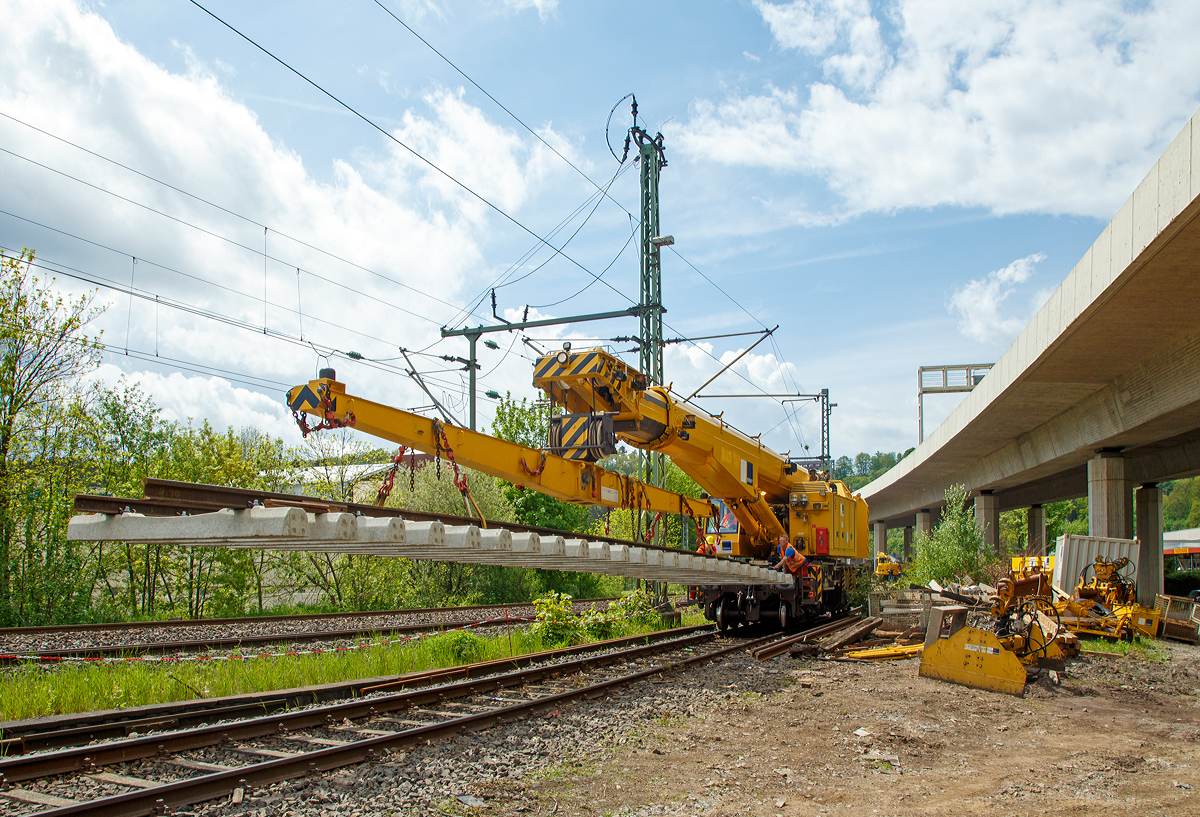 
Nun hat der 125t - KIROW Gleisbauschienenkran KRC 810 T der Hering Bau (Burbach), Schweres Nebenfahrzeug Nr. D-HGUI 99 80 9419 010-0, ein Gleisjoch an der Traverse und fährt am 09.05.2015 wieder Richtung Hauptbahnhof Siegen.

Die zwei Männer auf den Trittflächen müssen das Gleisjoch ruhig halten, damit es sich nicht unkontrolliert dreht oder schwankt.
