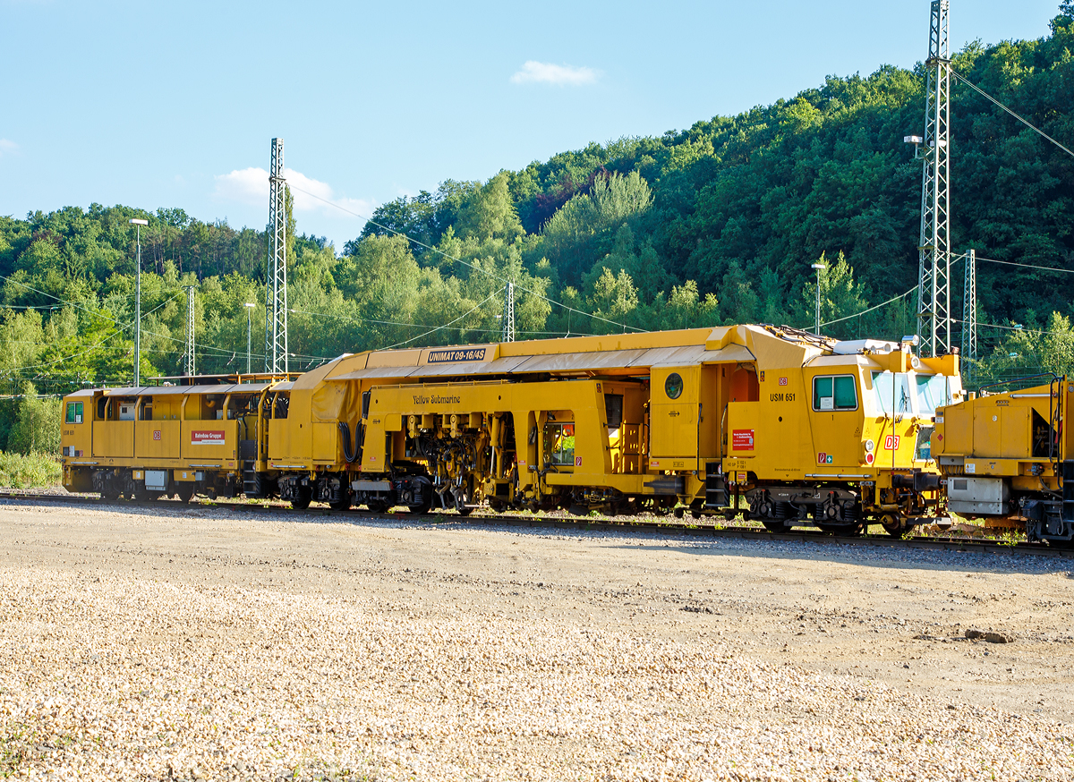 
Plasser & Theurer Universalstopfmaschine UNIMAT 09 - 16 / 4S (Schweres Nebenfahrzeug Nr. 97 43 51 001 17-3)  USM 651  „Yellow Submarine“  der DB Bahnbau Gruppe, abgestellt am 14.06.2017 in Betzdorf/Sieg abgestellt. Ehemals gehörte die Maschine der DB Netz AG, Maschinenpool (Netz Instandhaltung).

Die Universalstopfmaschine mit der internen DB Bezeichnung USM 651 wurde 2002 von Plasser & Theurer in Linz (A) unter der Fabriknummer 3023 gebaut.

Die Universalstopfmaschine Unimat 09-16/4S für Gleise und Weichen verfügt über vier unabhängig voneinander arbeitende Stopfaggregate mit insgesamt 16 Stopfpickeln. Bei der Gleisdurcharbeitung ist kontinuierliches Fahren und zyklisches Stopfen bis weit in den Weichenbereich hinein möglich

Funktionsmerkmale der USM Unimat 09-16/4S: 
- die vier Stopfaggregate können gedreht, einzeln seitlich verschoben und somit vor jedem Stopfgang optimal positioniert werden
- für das Stopfen von Langschwellen werden die außen liegenden Stopfaggregate mit horizontalen Teleskop-Führungssäulen seitlich ausgefahren (Vierstrang-Stopfung)
- kontinuierliches Fahren und zyklisches Stopfen bis weit in den Weichenbereich hinein
- Durcharbeitung von Weichen erfolgt mit Dreistrang-Hebung und Vierstrang-Stopfung
- eine automatisch arbeitende Zusatzeinrichtung gewährleistet die Hebung des dritten Stranges
- Richtungslaser zum Verlängern der Messbasis in der Geraden
- 6-Kanal-Schreiberanlage zur Dokumentation der Gleißlage und Arbeitsqualität 
- Vibrationsverdichter
- automatischer Leitcomputer ALC mit EM-SAT Datenverarbeitung
- automatische Toleranz-Überwachung für Arbeitsqualität der Maschine
- Korrektursteuerung für Höhe, Längshöhe, Richtung, Überhöhung

TECHNISCHE DATEN:
EBA-Nummer: EBA 00 A 11 003
Spurweite: 1.435 mm (Normalspur)
Anzahl der Achsen: 8 davon 4 angetrieben
Achsfolge: 2' 2'+Bo' Bo' 
Länge über Puffer:  33.140 mm
Drehzapfenabstände: 10.000 mm / 3.500 mm / 14.000 mm
Achsabstand im Drehgestell: 1.800 mm
Raddurchmesser (neu): 920 mm
Eigengewicht: 131.000 kg
Nutzlast: - t
Zul. Anhängelast: 60 t
Leistung: ca. 500 kW 
Zur Mitfahrt zugel. Personenzahl: 6
Kleister befahrbarer Gleisbogen: R = 120 m (Arbeitsradius  min.  150 m)
Zugelassen für Streckenklasse: C2 und höher
Höchstgeschwindigkeit: 100 km
Bremse: KE-GP mZ K
Bremsgewichte: G 102 t / P 108 t

Arbeitsleistung bei Durcharbeitung im Gleis:  600 m/h
Arbeitsleistung bei Durcharbeitung von Weichen : 1 /h
