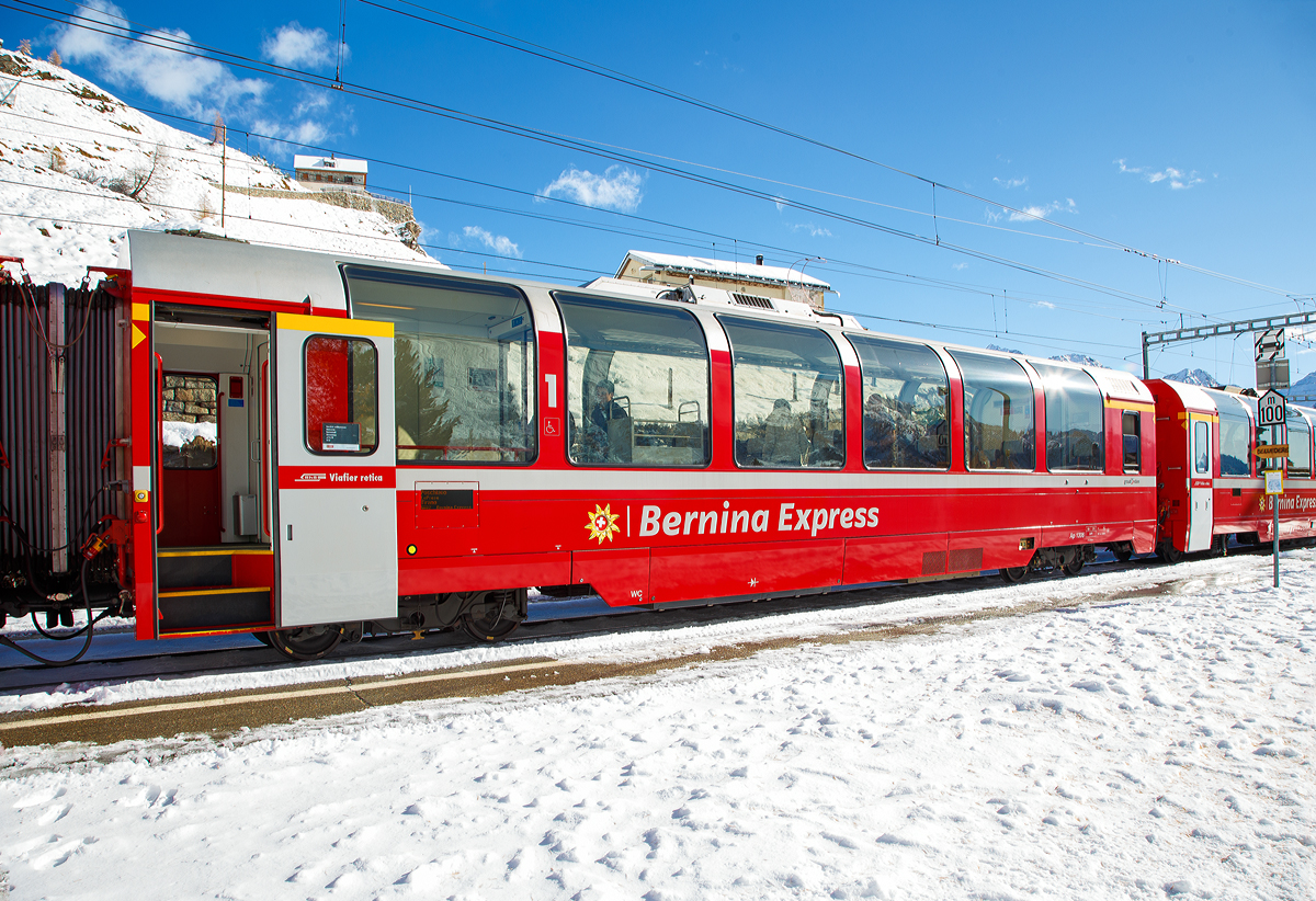 RhB Ap 1306 ein 1.Klasse Bernina-Express Panoramawagen der 2. Serie (Nachbau-Serie) am 04.11.2019, im Zugverband des BEX nach Tirano, beim Halt in Alp Gr�m.

F�r den ber�hmten Bernina-Express lie� die Rh�tische Bahn RhB 26 Panorama-Wagen in zwei Serienbauen. Gegen�ber den zuvor f�r andere Strecken gebauten Wagen, weisen die Bernina-Wagen eine um 3,2 m geringere Gesamtl�nge auf. Es entstanden neun 1.Klasse-  und siebzehn 2.Klasse-Wagen, die sich gro�er Beliebtheit bei den Fahrg�sten erfreuen. 

Um den Bernina-Express einheitlich mit Panoramawagen ausr�sten zu k�nnen, wurden 2006–2007 die 2.Serie von 16 Wagen (Api 1301–1306, Bps 2512–2515, Bp 2521–2526) als Nachbauserie beschafft. Diese erhielten nun allerdings luftgefederte Stadler-Drehgestelle und eine (vakuumgesteuerte) Druckluftbremse. Die vakuumgesteuerte Druckluftbremse wurde auch bei den bestehenden Wagen nachger�stet. Zudem wurde im Erstklasswagen eine rollstuhlg�ngige Toilette eingebaut. Da inzwischen das Rauchen in Schweizer Z�gen generell verboten wurde, konnte auch auf eine Trennwand f�r ein Raucherabteil verzichtet werden, bei den bisherigen Wagen wurde diese entfernt.

TECHNISCHE DATEN Ap-Wagen:
Baujahr: 2006/2007 
Hersteller: Stadler
Spurweite: 1.000 mm
Anzahl der Achsen: 4
L�nge �ber Kupplung: 16.450 mm
Breite: 2.650 mm
H�he: 3.540 mm
Fu�bodenh�he: 993 mm
Drehgestellart: luftgefederte Stadler-Drehgestelle
Achsabstand im Drehgestell: 1.800 mm
Laufraddurchmesser: 685 mm (neu)
Sitzpl�tze: 28
Stehpl�tze: 57
Eigengewicht: 18 t
Nutzlast: 6,4 t
zul�ssige Geschwindigkeit: 100 km/h
Lauff�hig: StN (Stammnetz) / BB (Berniabahn) / MGB (Matterhorn Gotthard Bahn)