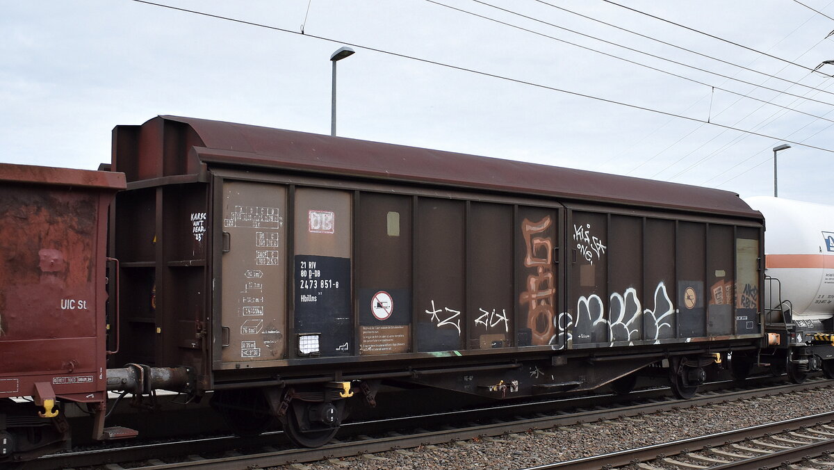 Schiebewandwagen mit zwei Radsätzen, zweiteiligen Aluminium-Schiebewänden und sechs verriegelbaren Trennwänden der DB Cargo mit der Nr. 21 RIV 80 D-DB 2473 851-8 Hbillns 302 in einem gemischten Güterzug am 04.11.25 Höhe Bahnhof Rodleben.