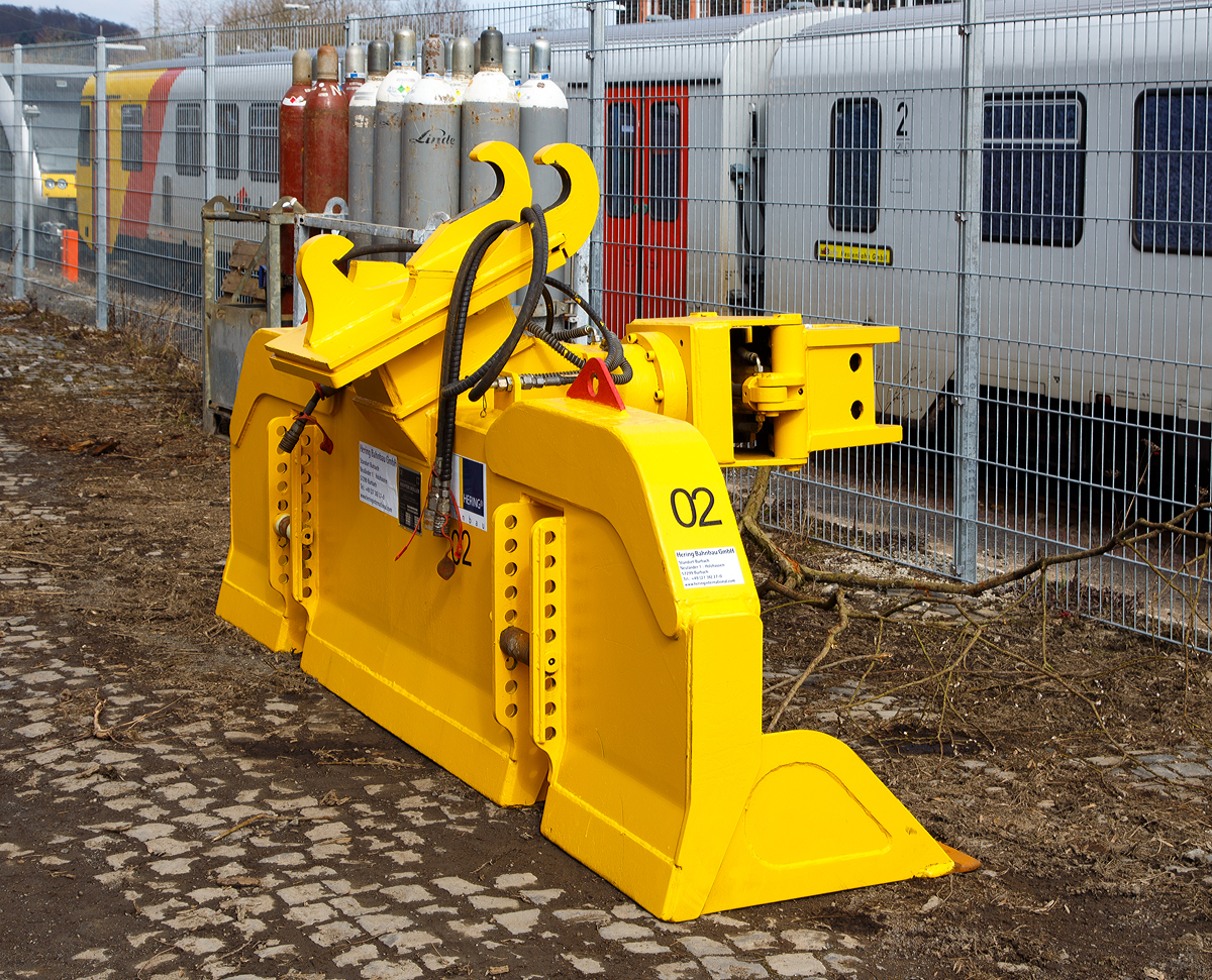 
Schwellenwechselgerät HSW der Hering Bahnbau GmbH, zum Anbau an einen Zweiwege-Bagger, abgestellt am 13.03.2016 beim Bahnhof Westerburg. 

Das Anbaugerät wurde 07/2011 von Richter & Müller Handelsgesellschaft mbH in Dormagen unter der Serien Nr. W8/N/L-005-8 gebaut. 

Das hydraulische Schwellenwechselgerät HSW ist ein Multifunktionsaggregat für den Aus- und Einbau des Gleisschotterbettes sowie für das Wechseln von Holz- und Betonschwellen. Die Aufnahme des Schwellenwechselgerätes sowie die hydraulische Energieversorgung erfolgt vom Zweiwege-Bagger.

Der Aus- und Einbau der Schwellen erfolgt durch eine hydraulische, 360° endlos drehbare Schwellenzange. Die Positionierung und Konstruktion dieser Zange wurde so gewählt, dass ein sicherer und schonender Aus- und Einbau aller gängigen Holz- und Betonschwellen gewährleistet ist. Es ist kein Wechseln der Zange erforderlich, auch bei unterschiedlichen Schwellenarten.

Um eine hohe Effektivität des Schwellenwechselgerätes zu erreichen, wurde das maximale Volumen bei den fest montierten Schaufelsegmenten gewählt.
Die Grabtiefe des Schwellenwechselgerätes HSW ist durch zwei verstellbare Rollen (die dann auf dem Gleis aufliegen) variabel und somit individuell einstellbar.

Technische Daten:
Gewicht:   1.300 kg
Breite:  2.800 mm
Betriebsdruck: 200 bar  
Spurweite:  1435 mm 