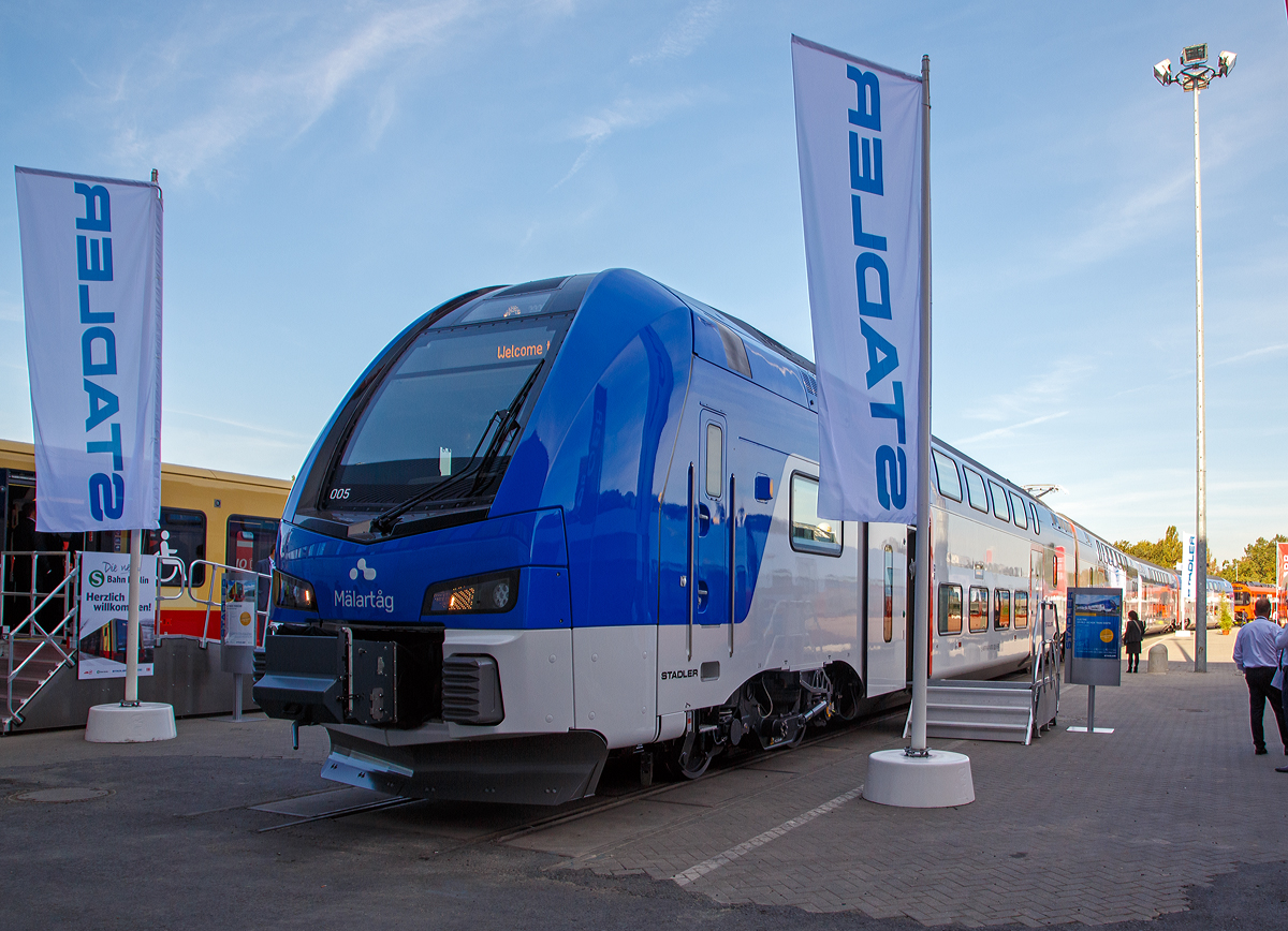 
Stadler pr�sentierte auf der InnoTrans 2018 (hier 18.09.2018) in Berlin den neuen f�r Schweden (ER1) bestimmten elektrischen Doppelstocktriebzug DOSTO  M�LART�G.

Das schwedische Leasing-Unternehmen AB Transitio hat f�r Betreiber M�LAB (M�lardalstrafik M�LAB AB) bei Stadler 33 vierst�ckige Elektro-DOSTO-Triebz�ge (KISS 200) bestellt. In Schweden haben die Z�ge die Typenbezeichnung ER1 erhalten und werden 2019 und 2020 ausgeliefert.

Die Z�ge sind f�r die Strecken Stockholm - Eskilstuna - �rebro, Stockholm - Katrineholm - Hallsberg, Stockholm - Nyk�ping - Norrk�ping und Sala - V�ster�s - Eskilstuna – Norrk�ping bestimmt. 

Mit einer H�chstgeschwindigkeit von 200 km/h wurden die Z�ge speziell f�r den Betrieb in schwedischen Wintern angepasst. Sie sind so konzipiert, dass sie bei minus 40 Grad und 80 cm Schnee auf der Strecke fahren k�nnen. 

TECHNISCHE DATEN:
Spurweite: 1.435 mm
Achsfolge: 2’ Bo’ + 2’ 2’ + Bo’ 2’ + Bo’2
L�nge �ber Kupplung: 104.810 mm
Breite: 2.920 mm
H�he: 4.700 mm
Raddurchmesser: 920 mm (neu)
Achsabstand im Drehgestell: 2.500 mm
Leergewicht: 232 t
Leistung (am Rad): 4.500 kW
H�chstgeschwindigkeit: 200 km/h
Anfahrzugkraft: 240 kN (bis 67 km/h)
Max. Beschleunigung: 0.95 m/s�
Stromsystem: 15 kV AC
Sitzpl�tze: 333 (plus 24 Klappsitze)
Einstiegsh�he: 605 mm
Fu�bodenh�he: 450 mm (Unterdeck) / 2.597 mm (Oberdeck)
Breite der T�r�ffnung: 1.300 mm
Deckenh�he: 2.000 mm
