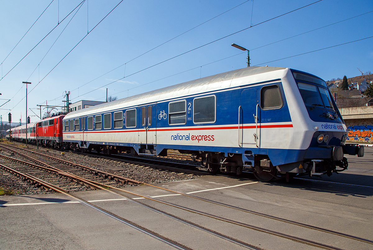 Steuerwagen voraus, Lok in den Zug eingereiht, fährt ein National Express Personenzug am 24.03.2021 durch Niederschelden, hier passiert er gerade den Bü 343 (Km 112,183 der Siegstrecke KBS 460).

Die Zugbildung war hier im Einzelnen: 
Der National Express 2.Klasse Nahverkehrs-Steuerwagen mit Wittenberger Kopf und Mehrzweckraum, D-TRAIN 50 80 80-35 128-3 der Gattung Bnrdzf 483.0 (ex BDnrzf 739.0. Der Wagen wurde 1995 vom AW Karlsruhe gebaut.
Die 111 200-2 (91 80 6111 200-2 D-GfF) der Gesellschaft für Fahrzeugtechnik mbH
Zwei National Express 2. Klasse Nahverkehrswagen (n-Wagen)
Am Zugschluss der National Express 2.Klasse Nahverkehrs-Steuerwagen mit Wittenberger Kopf und Mehrzweckraum, D-TRAIN 50 80 80-35 190-3 der Gattung Bnrdzf 483.1 (ex BDnrzf 740.2) der TRI Train Rental GmbH.  Der Wagen wurde 2003 vom AW Werk Delitzsch gebaut.

Die aus scheibengebremsten Steuerwagen der Bauart BDnrzf 739 und 740 umgebauten und mit einem Wittenberger Kopf ausgestatteten Wagen werden überwiegend als Bnrdzf 483 bezeichnet. 
Die bisher verwendeten Führerstände konnten nur entweder mit Diesel- oder Elektroloks eingesetzt werden. Um den Steuerwagen für die jeweils andere Traktionsart nutzbar zu machen, ist ein mehrstündiger Umbau des Führertisches erforderlich. Aus diesem Grund wurde Anfang der 1990er Jahre vom RAW Wittenberge der Prototyp eines neuen modularen Führerstandes entwickelt. Zum Einsatz kommt ein aus GFK vorgefertigtes Wagenkasten-Segment, in dem der mit der Baureihe 111 eingeführte DB-Einheitsführerstand installiert ist. Der Führerraum ist geräumig und übersichtlich gestaltet, zudem hat er seitliche Türen und eine verglaste Rückwand mit Dreh- oder Schiebetür, durch die der Blick vom Fahrgastraum nach vorne auf die Strecke möglich ist. Auf der technischen Seite wurde eine rechnergestützte Steuerung installiert, die den Betrieb sowohl mit der konventionellen Wendezugsteuerung als auch mit der neuen zeitmultiplexen Wendezugsteuerung, sowohl mit Diesel- als auch mit Elektrolokomotiven ermöglicht. Die Betriebsart wird lediglich umgeschaltet, es sind keine Umrüstungen mehr erforderlich. 

Die Wagen werden als „Wittenberger Kopf“ oder „Wittenberge-Steuerwagen“ bzw. „Wittenberger Steuerwagen“ bezeichnet.

TECHNISCHE DATEN des Bnrdzf 483.0 : 
Spurweite: 1.435 mm
Länge über Puffer:  26.400 mm
Wagenkastenlänge:  25.800 mm
Wagenkastenbreite:  2.825 mm
Höhe über Schienenoberkante: 4.050 mm
Drehzapfenabstand: 19.000 mm
Achsstand im Drehgestell:  2.500 mm
Drehgestell Bauart:  Minden-Deutz 432
Leergewicht:  32 t
Höchstgeschwindigkeit:  140 km/h
Bremsbauart: KE-GPR-A -mZ (D) [ep|NBÜ]
Sitzplätze:  76 in der 2. Klasse
Abteile: 2 Großräume 2. Klasse, 1 Mehrzweckraum 
Baujahre: 1995 bis 1995
Bemerkungen: uneingeschränkt dieselloktauglich
