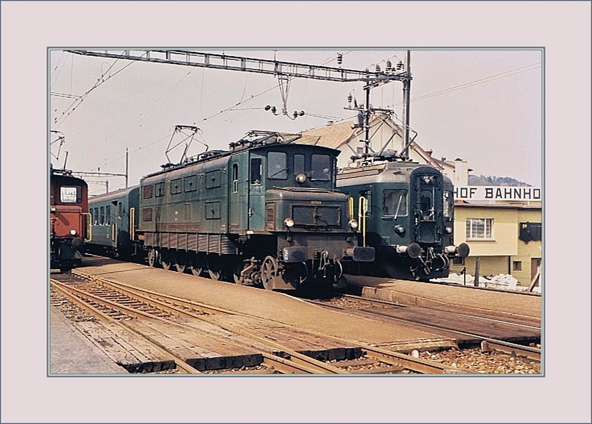 Trotz schlechter Bildqualität vermitteln diese kleine Bildserie recht eindrücklich die Nebenbahnstimmung einer Landstation in den 1980ern in Safenwil: Ein Regionalzug mit dem schiebendne RBDe 4/4 von Aarau nach Zofingen hält auf Gleis 3 während auf Gleis 2 eine Ae 4/7 mit dem Gegenzug (ev. ein  Stücker?) auf die Weiterfahrt wartet.
März 1985