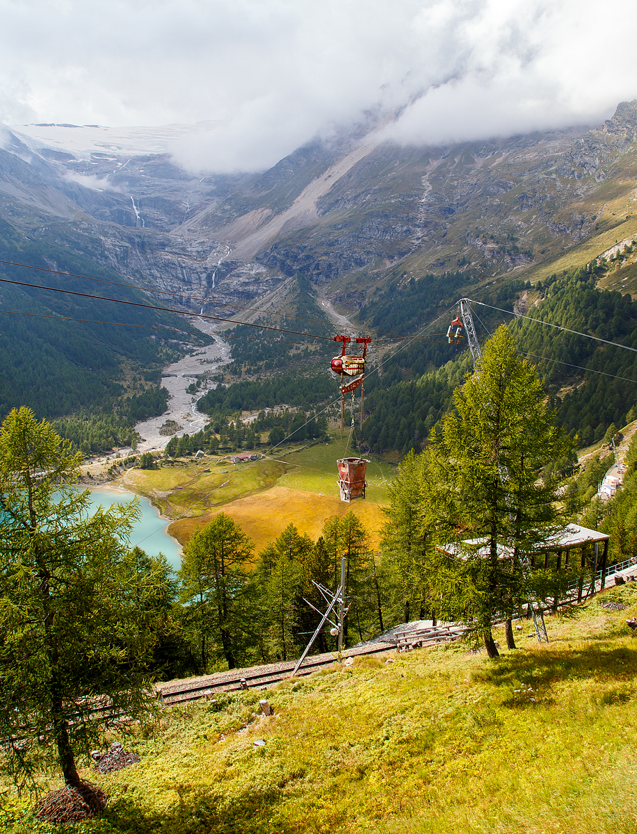 Unterhalb Alp Grüm werden die Alp Grüm der Berninabahn erneuert, daher gibt es eine Materialseilbahn von Alp Grüm hinab zu den Galerien, hier am 06.09.2021. So wird oben in Alp Grüm der Beton gemischt und dann mit der Seilbahn hinab gefahren. 

Die hier verwendete Bahn ist vom italienischen Seilbringungs-Spezialisten Seik (Truden). Der verwendete Wagen ist ein Seilkran vom Typ SFM 30/60.  In dem Seilkran befindet sich ein Verbrennungsmotor der das Hubwerk antreibt (dieser läuft nur bei der Hubbewegen) um wie hier den Betonkübel anzuheben und später wieder abzusenken. Die Hubkraft beträgt im Einzelzug 3t oder wie hier im Doppelzug mit dem Waagbalken 6t. Das Gesamtgewicht beträgt ca. 1t. Die Winde für das Zugseil kann nach Belieben (Bergseite – Talseite) platziert werden.