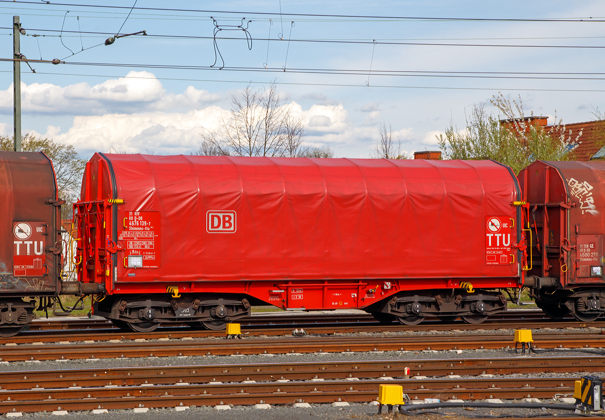 Vierachsiger Drehgestell-Flachwagen mit verschiebbarem Planenverdeck und Lademulden f�r Coiltransporte, 31 80 4676 137-7 D-DB, der Gattung Shimmns-ttu 708.4, der DB Cargo am 14.04.2018 im Zugverband bei der Durchfahrt im Bahnhof Friedberg (Hessen).

Man scheint in gro�en Schritten die alten Teleskophaubenwagen zu Planenwagen umzubauen.

Diese Wagen sind speziell f�r den Transport witterungsempfindlicher Blechrollen (Coils) bestimmt. Er besitzt feste Stirnw�nde, 5 fest im Untergestell eingebaute Lademulden. Die Wagenabdeckung erfolgt mit einer PVC-beschichteten Gewebeplane, die auf 11 Rohrrahmen aufliegt. �ber Laufwagen ist das Planendach in Wagenl�ngsrichtung verschiebbar. Die Verriegelung des Planendaches an den Stirnw�nden erfolgt �ber eine 4-Punkt-Zentralverriegelung, die sowohl vom Erdboden als auch von der Rampe aus bedient werden kann. Das Planenverdeck l�sst sich an einem Wagenende so weit zusammenschieben, dass ca. 2/3 der Ladefl�che zur Beladung freigegeben wird.Hierdurch ist eine einfache Beladung des Wagens sowohl von oben als auch von der Seite aus m�glich. 

Die Wagen der Bauart Shimmns 708 sind mit 12 verstellbaren Festlegearmen ausger�stet, die in fest auf den Muldenkappen angeordneten kammartig ausgef�hrten Halterungen gelagert sind. Die Festlegearme und ihre Anordnung ergeben einen wirksamen Schutz gegen unzul�ssiges seitliches Verschieben der Coils.

TECHNISCHE DATEN:
Spurweite: 1.435 mm
Achsanzahl: 4 (in 2 Drehgestelle)
L�nge �ber Puffer: 12.040 mm
L�nge der Ladefl�che: 10.800 mm
Drehzapfenabstand: 7.000 mm
Achsabstand im Drehgestell: 1.800 mm
Eigengewicht: 24.000 kg
H�chstgeschwindigkeit:  100  km/h (beladen) / 120 km/h (leer)
Maximales Ladegewicht: 66,0 t (Streckenklasse D4)
Kleinster bef. Gleisbogenradius: 35 m
Bauart der Bremse: KE-GP
Intern. Verwendungsf�higkeit: RIV