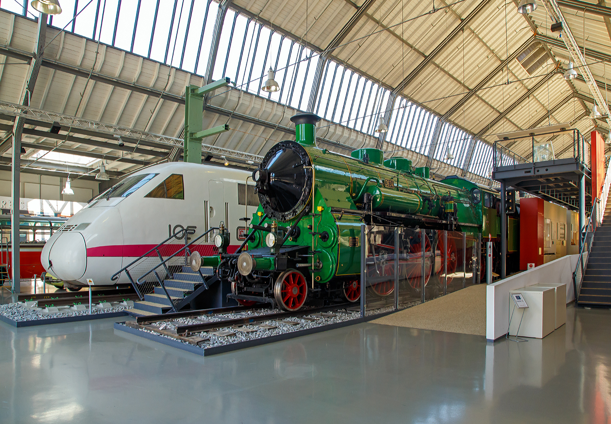 
Zwei Meilensteine der deutschen Schnellzüge....

Die Bayerische S 3/6 3634, spätere DRG und DB 18 451, und dahinter 410 002-0 der Triebkopf 2 vom ICE – V (InterCityExperimental bzw. ICExperimental), ex DB 745 002-6, (am 16.06.2018) ausgestellt im Verkehrszentrum des Deutschen Museums in München (Theresienhöhe).

Die S 3/6 3634 wurde 1912 von J.A. Maffei in München unter der Fabriknummer 3315 gebaut. Sie wurde von der  Deutsche Bundesbahn dem Deutschen Museum gestiftet. 
Der ICE-V Triebkopf 410 002-0 wurde 1985 von Thyssen-Henschel in Kassel unter der Fabriknummer 32850 gebaut. Es ist eine Leihgabe vom DB Museum. 

Die S 3/6 gilt aufgrund ihrer Eleganz als die schönste Schnellzuglokomotive der Länderbahnzeit. Die zwischen 1908 und 1931 produzierte Vierzylinder-Verbundmaschine zeichnete sich durch ihre große Laufruhe aus. Höhepunkt war ihr Einsatz als Zugmaschine des berühmten Luxuszuges „Rheingold-Express“, der ab 1928 zwischen Hoek van Holland und Basel verkehrte.

Die hier ausgestellte S 3/6 3634 der bayerischen Staatsbahn ist die Einzige erhalten gebliebene von 18 Lokomotiven der Bauserien „d“ und „e“, die einen von 1.870 auf 2.000 mm vergrößerten Treibraddurchmesser aufweisen. Sie bewährten sich besonders bei Schnellverbindungen, die ohne Zwischenhalt gefahren wurden und eine Geschwindigkeit von 90 bis 100 km/h erforderten. 1951 stellte die 18 451, wie sie nach der Einführung des Nummernschemas der Deutschen Reichsbahn hieß, einen Langstreckenrekord auf. Sie legte die 820 km betragende Strecke zwischen Hamburg und München mit einer Höchstgeschwindigkeit von 125 km /h ohne das übliche Ausschlacken des Feuers zurück. Als sie 1954 bei der DB ausgemustert wurde, hatte sie in ihrer 42- jährigen Betriebszeit 2,5 Millionen Kilometer zurückgelegt.

Technische Daten
Leistung: 1.770 PS
Gewicht: 89.500 kg
Höchstgeschwindigkeit: 120 km/h


Der InterCityExperimental / ICE-V wurde ab 1982 im Rahmen des Rad-/Schiene-Forschungsprogramms als Versuchszug von der Bahn gemeinsam mit Partnern der Bahn-Industrie entwickelt. Das Produkt war ein Zug mit zwei Triebköpfen und 3 Mittelwagen. Er wurde als Baureihe 410/810 am 31.07.1985 ausgeliefert und erhielt zunächst den Namen ICE (Inter-City-Experimental). Er diente als Demonstrationsfahrzeug und Versuchs-Triebzug der Deutschen Bundesbahn für die Erprobung des Hochgeschwindigkeitsverkehrs in der Bundesrepublik Deutschland und Vorläufer der heutigen Intercity-Express-Züge der Deutschen Bahn AG.

Mit dem Zug hat die Bahn die technischen und wirtschaftlichen Grenzbereiche des Rad-Schiene-Systems erforscht und so die Voraussetzungen für den Hochgeschwindigkeitsverkehr geschaffen. Ein wesentlicher Baustein waren auch die aerodynamischen Versuche, deren Ergebnisse das stromlinienförmige Profil der heutigen ICE bestimmt haben.

Der ICE-V 410 002 erreichte am 1. Mai 1988 auf seiner Weltrekordfahrt eine Höchstgeschwindigkeit von 406,9 km/h und überbot damit den Geschwindigkeitsweltrekord für Rad-Schienen-Fahrzeuge.

Der ICE-V hat daneben alle Testfahrten ausgeführt, die für die Zulassung der Neubaustrecken Hannover – Würzburg, Mannheim – Stuttgart und Hannover – Berlin erforderlich waren. Am 01.06.1998 wurde der ICE-V nach 13 Jahren Versuchsbetrieb und 500 000 km Laufleistung ausgemustert.

Technische Daten:
Antrieb: 4 Drehstrom-Asynchronmotore je Triebkopf
Leistung: 	 x 1050 kW je Triebkopf
Gesamtleistung: 	8.400 kW (ca. 11.400 PS)
Höchstgeschwindigkeit (zugelassen):  350 km/h
Gewicht des Zuges: 296 t
Länge des Zuges:  113 m

