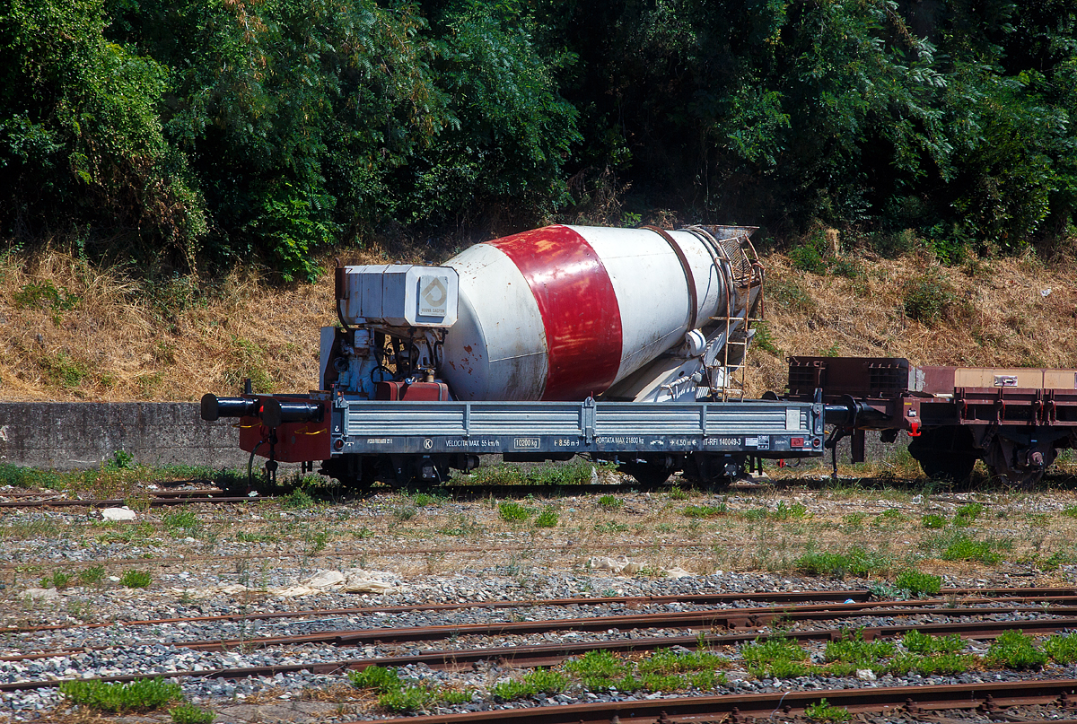 Zweiachsiger Niederflur-Flachwagen mit Seitenwandklappen, IT-RFI 140 049-3, mit darauf befindlichen Betonmischer (Fahrmischer), abgestellt am 16.07.2022 beim Bahnhof Agropoli (Region Kampanien – Italien). Aufnahme aus einem IC durch die Scheibe.

TECHNISCHE DATEN (laut Anschriften):
Spurweite: 1.435 mm
Achsanzahl: 2
Länge über Puffer: 8.560 mm
Achsabstand: 4.500 mm
Höchstgeschwindigkeit: 55 km/h
Eigengewicht: 10.200 kg
Max. Zuladung: 21.800 kg (einschl. Eigengewicht des Mischers)