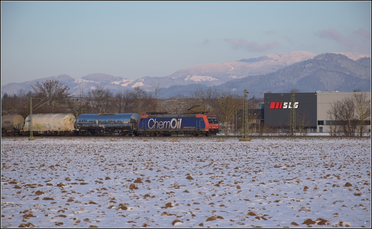 Zwischen Belchensystem und Blauendreieck. 

SBB Cargo Re 482 015 mit ChemOil-Werbung Richtung Basel bei Buggingen, während sich im Hintergrund der Schauinsland aus den Wolken geschält hat. Februar 2021.