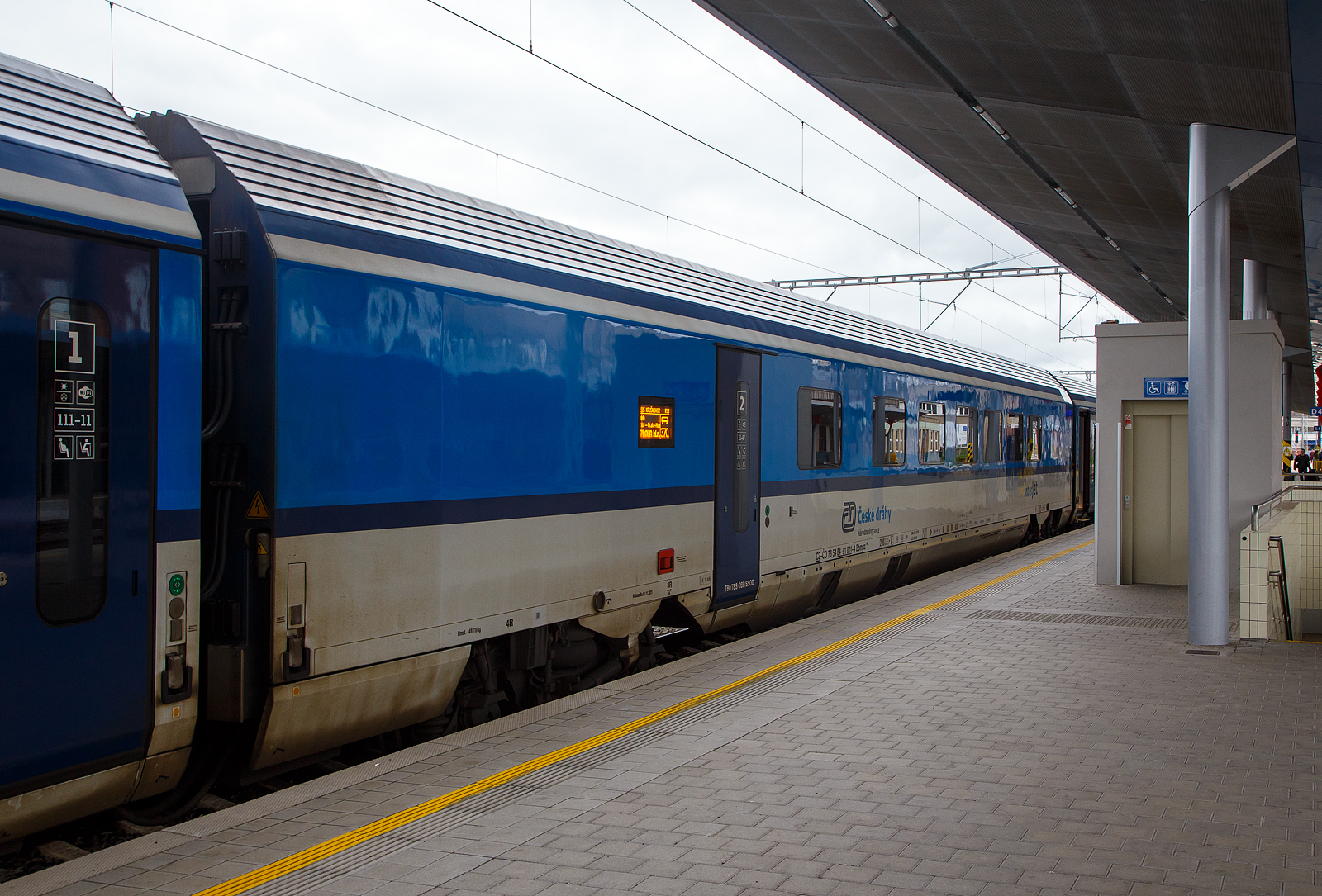 2. Klasse ČD InterJet Gro�raumwagen mit Behinderten-Hebeb�hnen, Behindertenabteil sowie Kinderabteil und Platz f�r Kinderwagen, CZ- ČD 73 54 84-91 001-4 der Gattung Bbmpz 897 der ČD - Česk� dr�hy (Tschechische Bahnen), eingereiht als Wagen 370 in den R15 „Kru�nohor“ (Cheb - Karlovy Vary - �st� nad Labem hl.n. - Praha hl.n.), am 17.04.2023 im Bahnhof Cheb (Eger).

Dieser wurde 2019 von Siemens Wien (Fertigung) und �KODA VAGONKA Ostrava (Montage) gebaut.   

Die ČD bestellte 50 Reisezugwagen, in Form von 10 f�nfteiligen Wageneinheiten die im regul�ren Betrieb fest verbunden sind. Diese UIC-Z-Wagen wurden zwischen 2019 und 2022 von Siemens Wien (Fertigung) und �KODA VAGONKA Ostrava (Montage) gebaut. Die Einheiten haben keinen Steuerwagen, sie sind an beiden Enden mit Schraubkupplungen  und Puffern (Standard Zug-Sto�-Einrichtung) ausgestattet. Man geht davon aus, dass sie auf den Strecken Prag – Pilsen – Cheb und Prag – �st� nad Labem – Chomutov – Cheb eingesetzt werden. Eine Einheit besteht aus einem 1.-Klasse-Wagen, einem 2.-Klasse-Wagen mit Platz f�r Rollstuhlfahrer und f�r Reisende mit Kindern, zwei 2.-Klasse-Wagen ohne Sonderausstattung und einem 2.-Klasse-Wagen mit Platz f�r den Fahrradtransport.

TECHNISCHE DATEN:
Spurweite: 1.435 mm (Normalspur)
Achsanzahl: 4
L�nge �ber Puffer: 26.400 mm
L�nge des Wagenkastens: 26.100 mm
Drehzapfenabstand: 19.000 mm
Breite: 2.825 mm
H�he: 4.050 mm
H�chstgeschwindigkeit: 200 km/h   
Leergewicht: 48,81 t
Sitzpl�tze: 50 in der 2. Klasse
Rollstuhlpl�tze: 3
Toiletten: 2, geschlossenes System