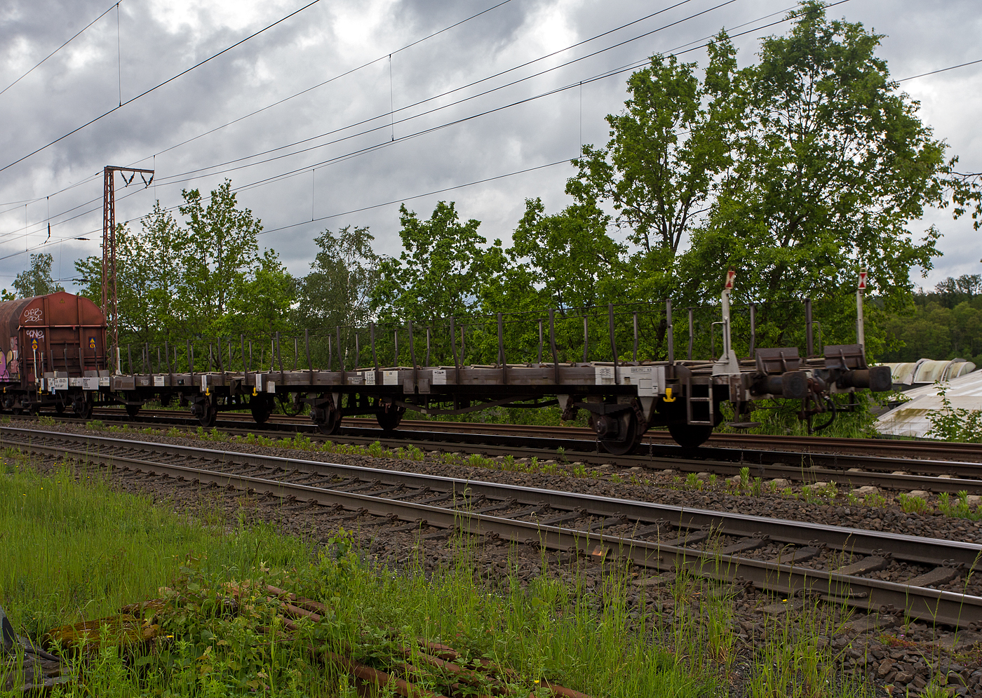 2 x 2 achsiger leere offener Autotransportwaggoneinheit 25 80 4354 025-5 D-ATG der Gattung Laadrs 557 der DB Cargo Logistics GmbH (ex ATG Autotransportlogistic GmbH) am 22 Mai 2024 im Zugverband bei der Zugdurchfahrt in Rudersdorf (Kreis Siegen).

Diese Wageneinheiten verfügen nur über eine Ladeebene und sind speziell für den europaweiten Transport von hohen Fahrzeugen wie beispielsweise Kleintransportern oder leichten Nutzfahrzeugen vorgesehen. Je nach Bauart können die Wagen mit 5 bis 6 Fahrzeugen beladen werden. Zur Ladungssicherung befinden sich auf der Ladeebene 48 Radvorleger. Diese Wagen wurden ab 1985 als Leks 558 gebaut und 1996 zu diesen Laadrs 557 umgebaut.

TECHNISCHE DATEN:
Gattung: Laadrs 557
Spurweite: 1.435 mm (Normalspur)
Anzahl der Achsen: 4 (2 x 2)
Länge über Puffer : 31.000 mm
Ladelänge : 30.000 mm
Höhe der Ladefläche über SOK: 1.165 mm
Achsabstände: 9.000 / 6.240 / 9.000 mm
Höchstgeschwindigkeit: 100 km/h (beladen) / 120 km/h (leer)
Eigengewicht: 28.000 kg
Nutzlast: 24,0  t ab Streckenklasse A 
Zulässige Radlast der Ladung (Transporter): 800 kg
Kleinster befahrbarer Gleisbogenhalbmesser: R =75 m
Bremse: KE-GP-A (LL)
Intern. Verwendungsfähigkeit: RIV
