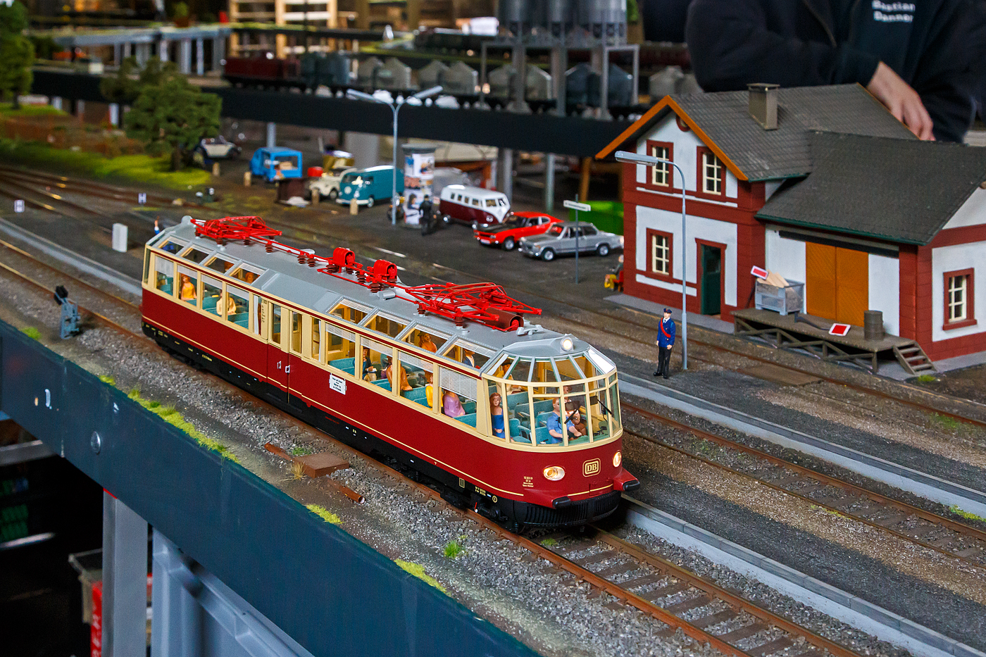 Als Spur 1-Modell, der ehemalige ET 91 01 „Gläserner Zug“, ex DRG elT 1998, spätere DB 491 001-4, hier in Farbgebung purpurrot/beige, mit 2 DBS 54-Stromabnehmer der Betriebszeit 1954 bis Anfang der 1960er Jahre (Epoche 3), am 02.07.2023 auf der Spur1-Anlage im Lokschuppen vom Erlebnisbahnhof Westerwald der Westerwälder Eisenbahnfreunde 44 508 e. V., hier war Lokschuppen-/Sommerfest.

Der Aussichtstriebwagen ET91, als „Gläserner Zug“ bekannt, wurde 1935 auf der Ausstellung „100 Jahre Deutsche Eisenbahn“ in Nürnberg dem Publikum vorgestellt. Mit den weiteren Aussichtstriebwagen, die dieselhydraulisch angetrieben wurden, versuchte die Deutsche Reichsbahngesellschaft der zunehmenden Konkurrenz des Omnibusses entgegenzuwirken und das Reisen mit der Eisenbahn attraktiver zu gestalten. Um mehr Aussicht zu bieten, hat man den schrägen Dachteil auch mit Fenstern versehen und auf die üblichen Gepäckträger verzichtet. Außerdem wurde der Abort im Einstiegsbereich möglichst niedrig gehalten und an Trennwänden im Inneren des Wagens ist der obere Teil verglast. So ist es gelungen, gute Sichtverhältnisse von allen Plätzen zu schaffen.

In der Reichsbahnzeit war das Einsatzgebiet der zwei elektrischen Triebwagen wegen der mangelnden Elektrifizierung des Schienennetzes relativ begrenzt. Aber schon im Winter 1936/37 waren sie auch auf Strecken der ÖBB eingesetzt. Im Mai 1943 wurde der zweite Triebwagen ET91.02 bei einem Bombenangriff auf München zerstört, worauf der ET91.01 außerhalb Münchens sicher abgestellt und sogar eingemauert wurde. 1949 wurde der ET91.01 in Bww München-Pasing betriebsfähig aufbereitet und kam ab Sommer wieder zum Einsatz. Nach dem Ausbau des Netzes erreichte er nicht nur Aachen, Hamburg, Wien und Graz, sondern kam häufig im Ausland zum Einsatz: in Oberlitalien, Frankreich, Luxembourg, Jugoslawien. Vor allem in Österreich und in der Schweiz war er öfters unterwegs, weshalb einer von Stromabnehmern 1976 durch einen Einholmstromabnehmer ersetzt wurde. Nach der Wende durfte er dann auch das bis dahin verbotene Terrain, das Netz der DR betreten. Am 12. Dez. 1995 stieß der Gläserne Zug in Garmisch-Patenkirchen mit einer ÖBB-Lok frontal zusammen, an dessen Folge er 1997 aus dem Bestand der DB gestrichen und seit 2005 im Bahnpark Augsburg abgestellt wurde.

TECHNISCHE DATEN der ET 91/BR 491:
Gebaute Stückzahl: 2
Baujahr: 1935
Hersteller (mech.): Waggonfabrik Fuchs, Heidelberg
Hersteller (elektrisch): AEG, Berlin
Spurweite: 1.435 mm (Normalspur)
Achsanordnung: Bo´2´
Gattung: C 4
Länge über Puffer: 20.600 mm
Drehzapfenabstand: 13.815 mm
Achsabstand im Triebdrehgestell: 3.600 mm
Achsabstand im Laufdrehgestell: 3.000 mm
Trieb- und Laufraddurchmesser: 950 mm (neu)
Leergewicht: 50,8 t
Dienstgewicht: 54,5t (voll besetzt)
Höchstgeschwindigkeit: 110 km/h (ursprünglich 120 km/h)
Leistung: 390 kW
Dauerleistung bei 74 km/h: 350 kW
Stromsystem: 15 kV, 16 2/3 Hz ~
Sitzplätze: 	70
Antrieb: Tatzantrieb
