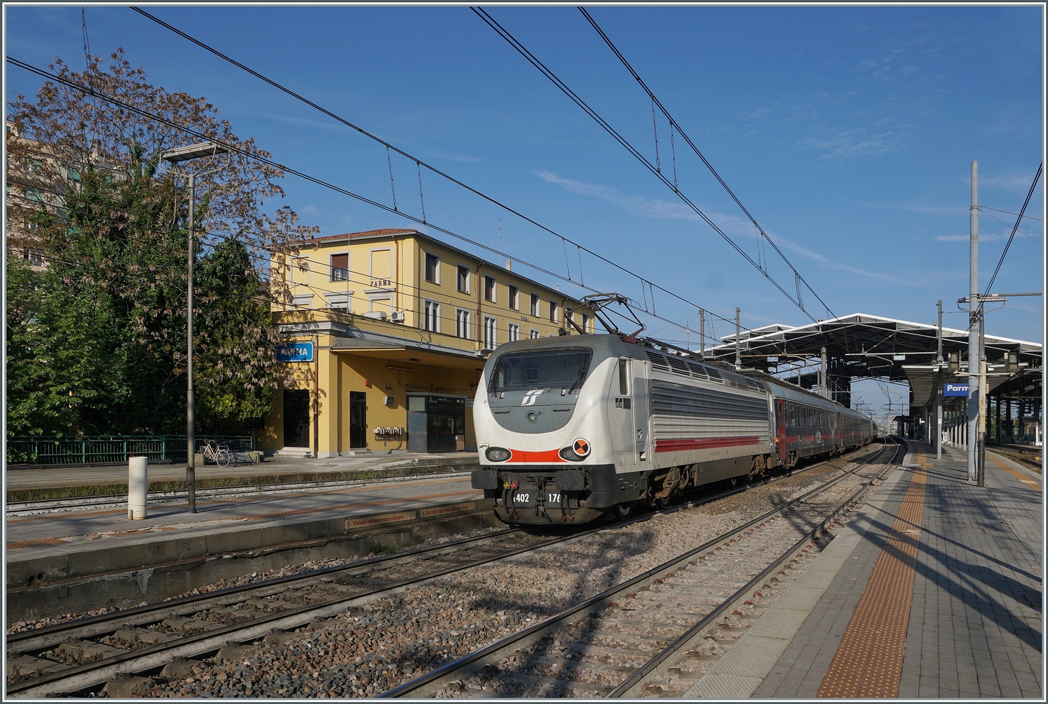 Am Schluss der Nachtzuges von Sizilien nach Milano schiebt die FS 402 176, die sich in Parma im sch�nsten Morgenlicht zeigt.

18. April 2023
