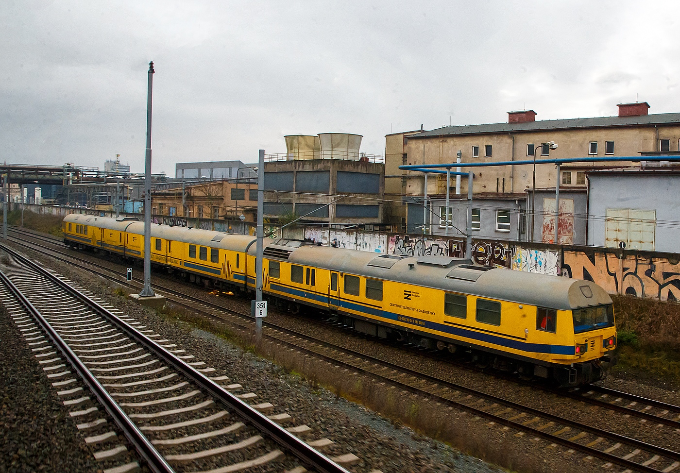 Bei Plzeň Ji�n� předměst� f�hrt am 24.11.2022 �ber die Bahnstrecke Cheb – Plzeň der S�DC Schienenpr�fzug (DJ NTD – Diagnostika Kolejnic / Diagnosezug mit Ultraschall- und Wirbelstrompr�ftechnik) S�DC 162 002-8 / 362 003-4 / 362 004-2 (CZ- SZCZ 99 54 9 162 002-8 / CZ- SZCZ 99 54 9 362 003-4 / CZ- SZCZ 99 54 9 362 004-2) der Spr�va �eleznic (S�CZ), in Richtung Pilsen. (Aufnahme aus einem alex-Zug)

Der Schienenpr�fzug wurde 2017 von der Firma NDCon Logic in Zusammenarbeit mit den Firmen MAV KFV (Budapest), Tvema (Moskau), PLR (Magdeburg) und CZ Loko (Česk� Třebov�) gebaut.Er dient zur Erkennung von inneren Fehlern an Schienen, die durch Ultraschall- und Wirbelstrompr�ftechnik erkannt werde. 

Der Zur ist dreiteilig und besteht aus;

Dem vierachsigen Motorwagen 162 002-8, dieser ist ein umgebauter und komplett modernisierter Verbrennungstriebwagen mit hydraulischer Kraft�bertragung der ČD Baureihe 851 (ex ČSD-Baureihe M 286.1), hier am Zugschluss. Diese VT mit der Achsfolge 2' B' der ČSD-Baureihe M 286.1 sp�ter ČD 851wurden 1967–1968 von Vag�nka Tatra Stud�nka und haben eine etwas h�herer Leistung (588 kW) als die BR 850. Die Leistung kommt von einem 12-Zylinder-V-Motor vom Typ ČKD KS 12 V 170 DR, die Leitungs�bertragung geschieht �ber eine elastische Kupplung und eine Gelenkwelle mit dem hydrodynamischen Getriebe H 750 M mit drei Wandlern verbunden.

Dem Mittelwagen/Messwagen 362 003-4 einem umgebauten vierachsigen 24.500 mm langen ehemaligen ČSD Post w-Wagen (Y-Wagen). In ihm sind Messger�te, der Messraum und R�ume f�r Nebenaggregate (Diesel-Stromaggregat), Betriebswassertanks (8 x 1.000 Liter mit technologischem Wasser), ein Lager sowie eine Werkstatt.

Und dem Steuerwagen, dieser wurde auch aus einem vierachsigen ČSD Post w-Wagen umgebaut und bekam an der Wagenfront einen F�hrerstand. In ihm ist ein Wohn-/Schlafbereich mit 3 Einzelbettabteilen, Sanit�ranlagen mit geschlossenem System, ein Essbereich und einem Besprechungsraum, sowie 4 x 1.000 Liter Betriebswassertanks (mit technologischen Wasser).

TECHNISCHE DATEN:
Spurweite: 1.435 mm (Normalspur)
Anzahl der Achsen: 12 (3 x 4)
L�nge �ber Puffer:  73.800 mm (VT 24.790 mm / 2 x 24.500 mm)
Breite: 2.880 mm
Gesamtgewicht: 150.360 kg
H�chstgeschwindigkeit: 110 km/h 
Max. Geschwindigkeit bei Messfahrt: 70 km/h
Vorrat technologisches Wasser (als Koppelmittel f�r Pr�fung): 12.000 l
Messleistung mit einem Wasservorrat:  ca. 200 km

Quellen: Spr�va �eleznic, Wikipedia
