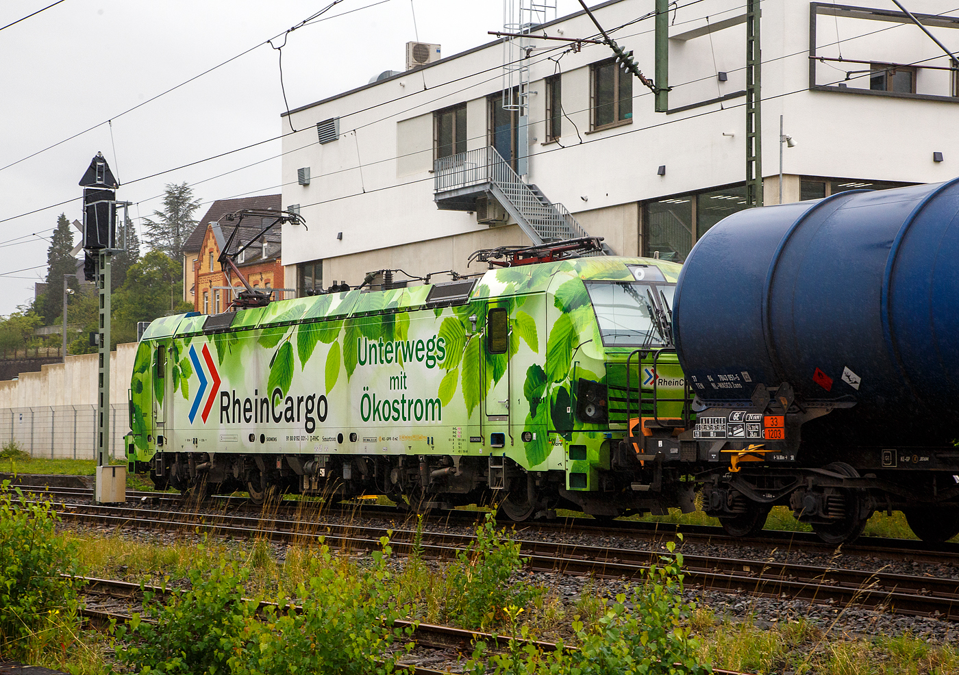 Bei Regen „Unterwegs mit �kostrom“, die SIEMENS Smartron 192 031-3 (91 80 6192 031-3 D-RHC), bzw. Lok 3001 der RheinCargo GmbH & Co. KG f�hrt man 03.08.2023 mit einem sehr langen Kesselwagenzug durch Niederschelderh�tte in Richtung K�ln. Die Ladung der Kesselwagen war laut Gefahrgutkennzeichnung (30/1202) Dieselkraftstoff beziehungsweise leichtes Heiz�l.

Die Smartron wurde 2020 von Siemens Mobilitiy in M�nchen-Allach unter der Fabriknummer 22889 gebaut. 
