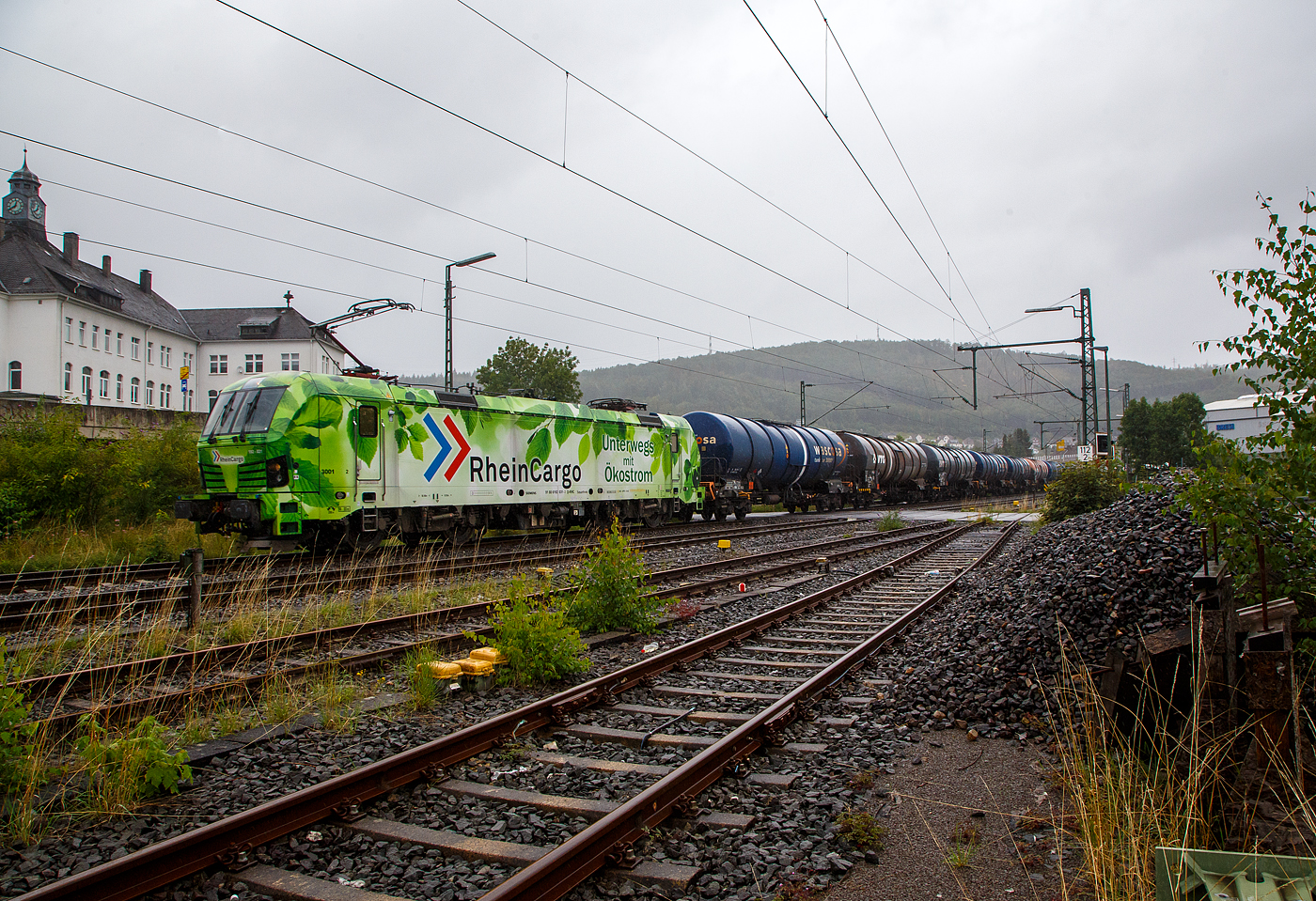 Bei Regen „Unterwegs mit �kostrom“, die SIEMENS Smartron 192 031-3 (91 80 6192 031-3 D-RHC), bzw. Lok 3001 der RheinCargo GmbH & Co. KG f�hrt man 03.08.2023 mit einem sehr langen Kesselwagenzug durch Niederschelderh�tte in Richtung K�ln. Die Ladung der Kesselwagen war laut Gefahrgutkennzeichnung (30/1202) Dieselkraftstoff beziehungsweise leichtes Heiz�l.

Die Smartron wurde 2020 von Siemens Mobilitiy in M�nchen-Allach unter der Fabriknummer 22889 gebaut. 
