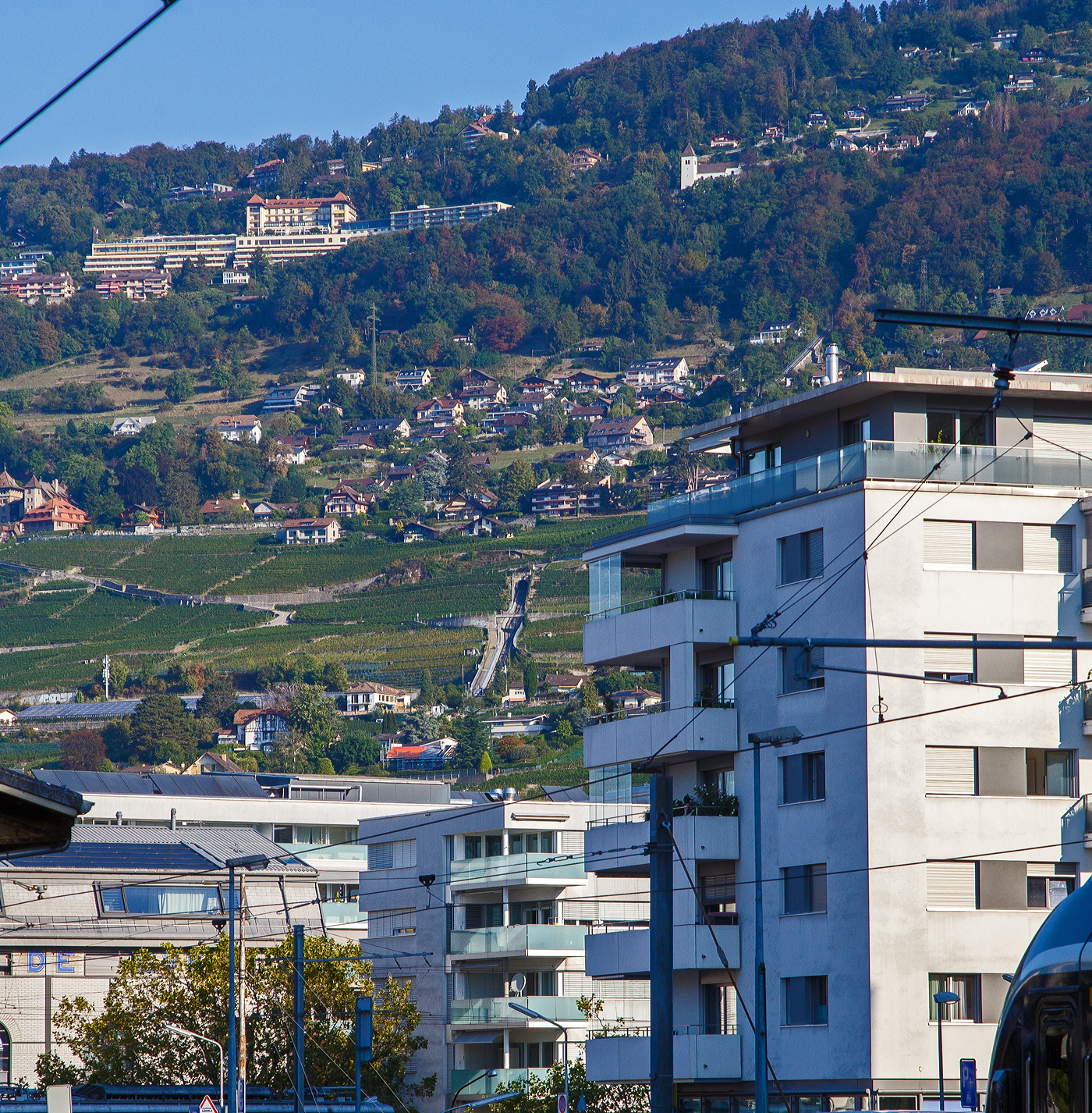 Blick (Detailbild) vom Bahnhof Vevey auf die Kreuzungstation (Chem. de Forchy, Chardonne) bzw. die abtsche Weichen (auch Abt´sche Weiche oder abtsche Ausweiche) der Standseilbahn Vevey–Chardonne–Mont-Pèlerin (VCP), leider ohne Seilbahnwagen, am 10.09.2023. 

Die Standseilbahn wurde 1900 eröffnet. Sie hat eine Streckenlänge von 1580 Metern und überwindet einen Höhenunterschied von 415 Metern. Neben der Tal- und Bergstation hat sie noch drei Zwischenhaltestellen.

Die Standseilbahn wurde am 25. September 2009 nach längerer Modernisierung, wobei auch die beiden Standseilbahnwagen einen neuen Aufbau erhielten, wieder in Betrieb genommen.

Die Standseilbahnlinie ab Vevey bietet eine unvergleichliche Aussicht auf die Schätze des Lavaux. Nur  ein paar Meter vom Bahnhof Vevey-Funi  entfernt verlässt die Standseilbahn Vevey am Genfersee und beginnt ihren steilen Aufstieg, vorbei an den Weinbergen des Lavaux, einem UNESCO-Weltkulturerbe, bringt einen die Standseilbahn Vevey – Chardonne – Mont-Pèlerin in 11 Minuten auf über 810 Meter Höhe. Ihr Ziel ist das Winzerdorf Chardonne-Baumaroche mit seinen Weinkellern und einer der schönsten Aussichten auf den Genfersee. Die Bergstation befindet sich aber nicht auf dem Gipfel des Mont-Pèlerin, um auf die Spitze des Mont-Pèlerin zu gelangen, erfordert es von der Bergstation einen 45 minütigen Fußmarsch.
